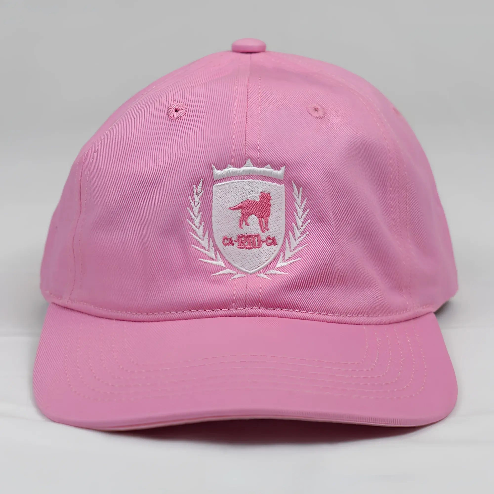 Pink cotton ca-rio-ca crest logo embroidered baseball cap with white shield emblem featuring pink dog and laurel wreath