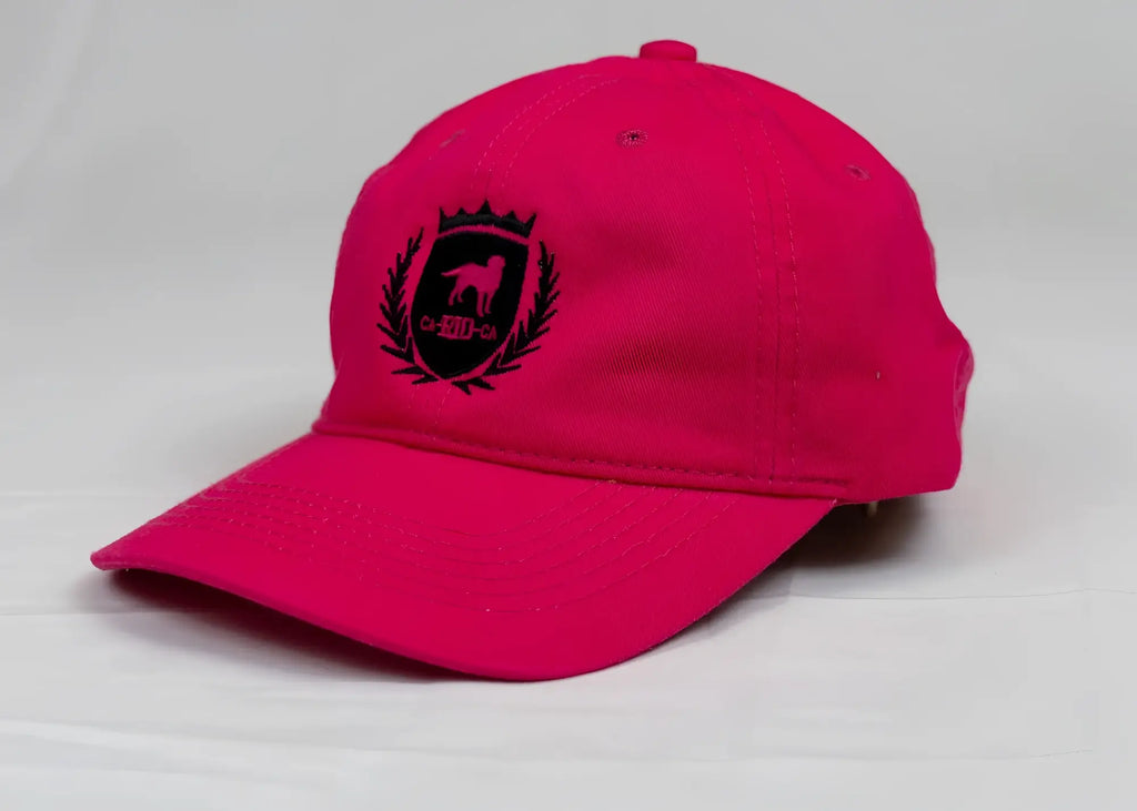 A vibrant pink ca-rio-ca designer dad hat with black embroidered dog crest and laurel wreath on the front