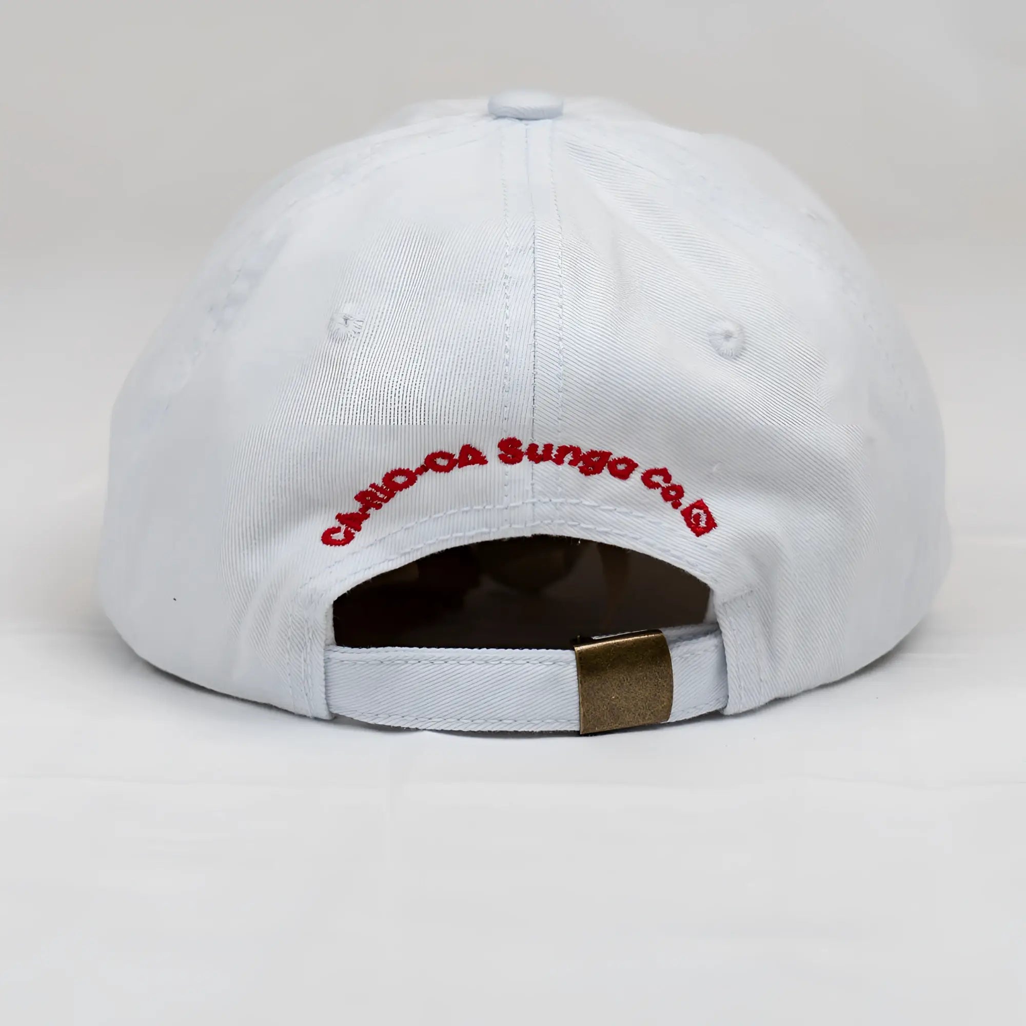 White ca-rio-ca crest logo embroidered designer dad hat with red text and brass metal buckle back view