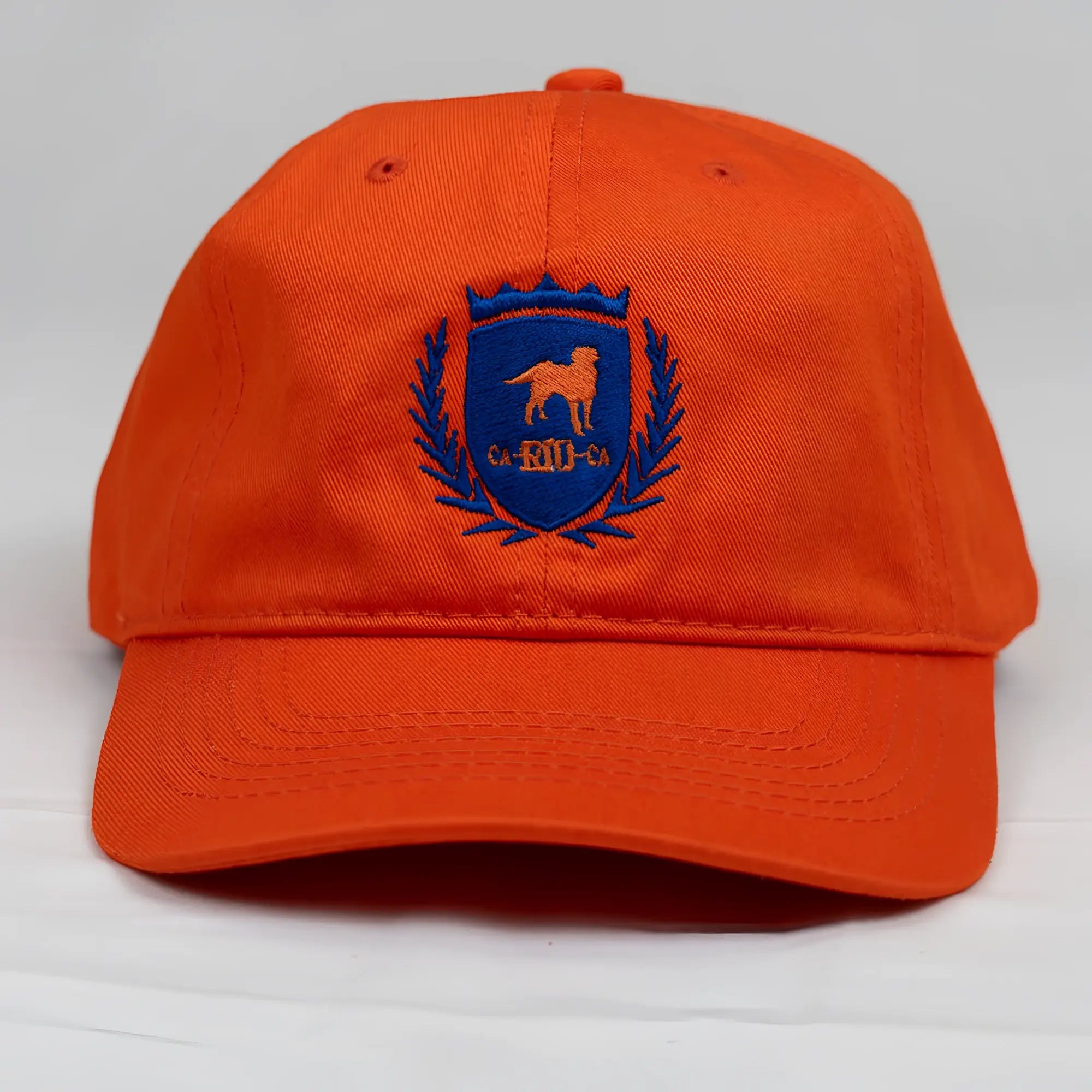 Vibrant orange cotton ca-rio-ca crest logo embroidered designer dad hat with blue shield and laurel wreath detailing