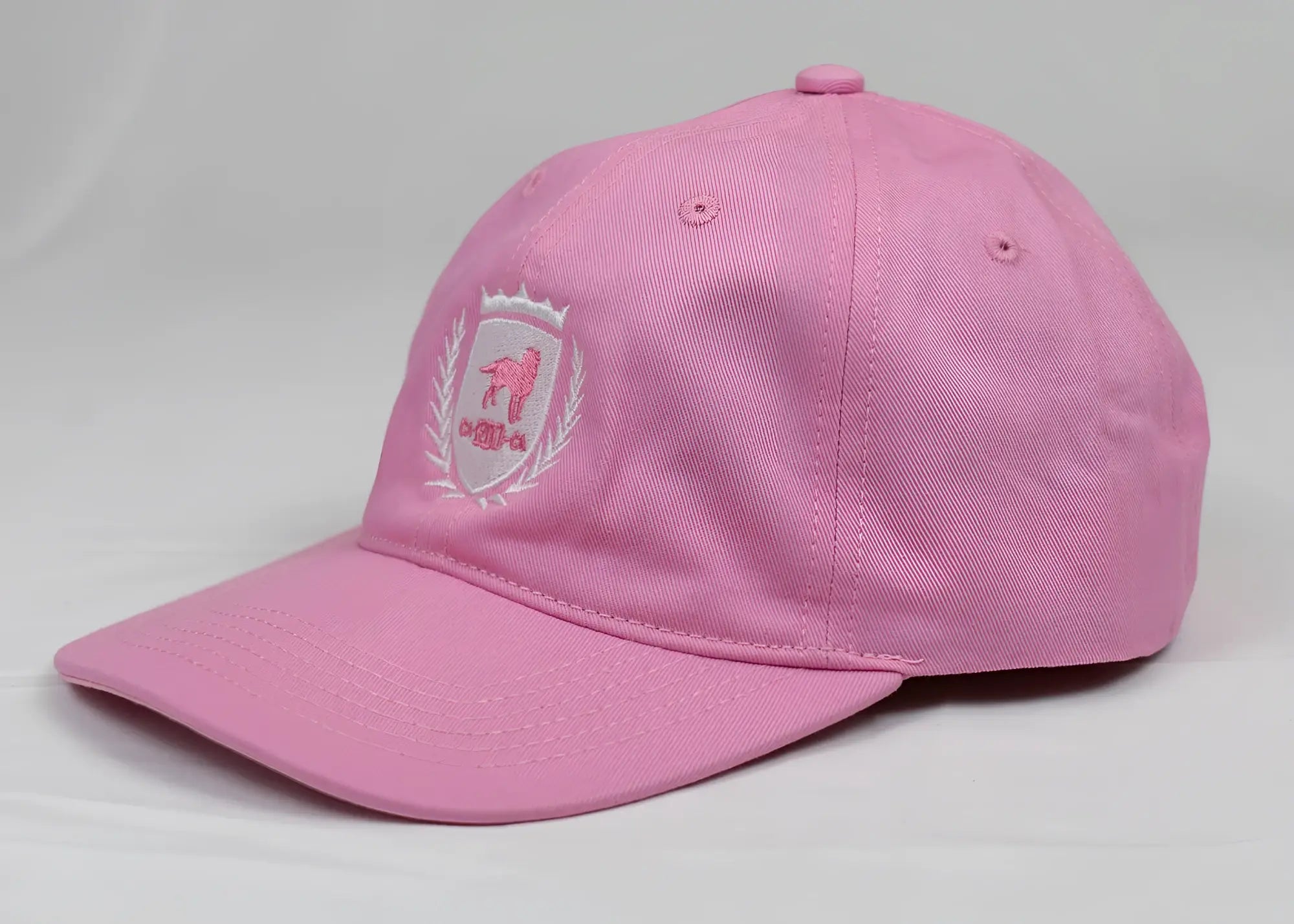 Pink baseball cap with embroidered ca-rio-ca crest logo featuring a pink dog and white laurel wreath