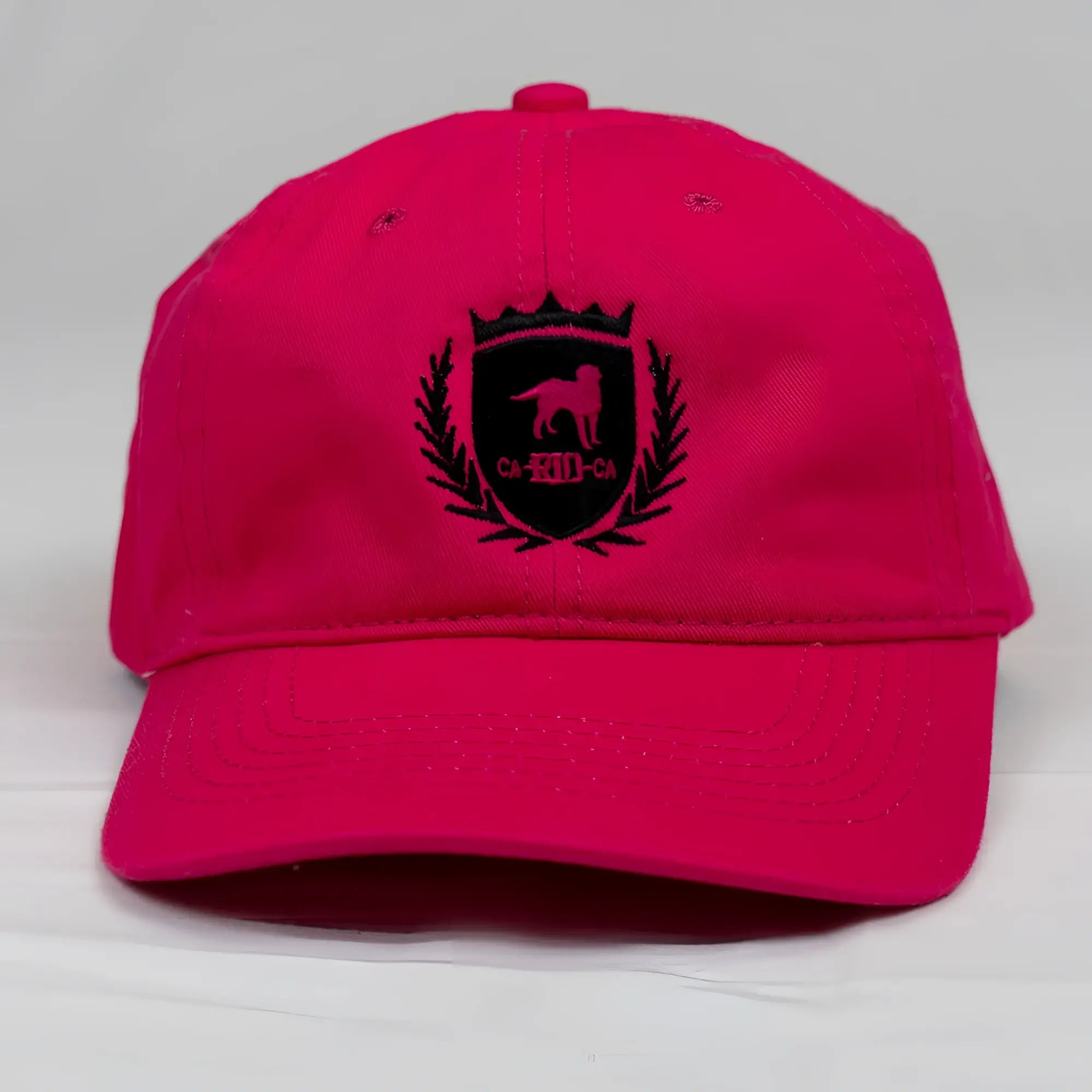 Vibrant pink cotton CA-RIO-CA crest logo embroidered designer dad hat with black dog silhouette crown and laurel wreath