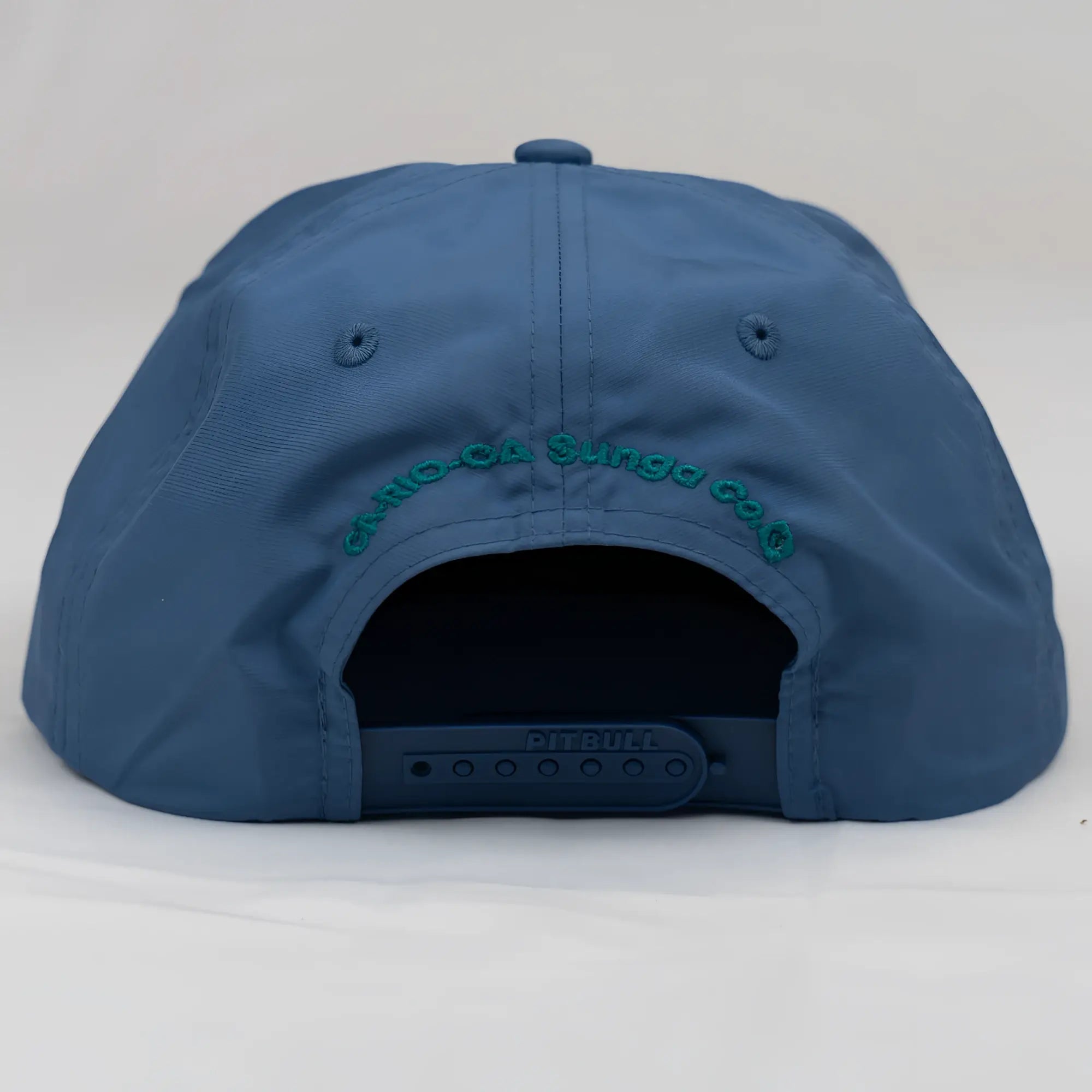 Blue unstructured bay leaf snapback rope hat with teal embroidered crest logo and black adjustable strap