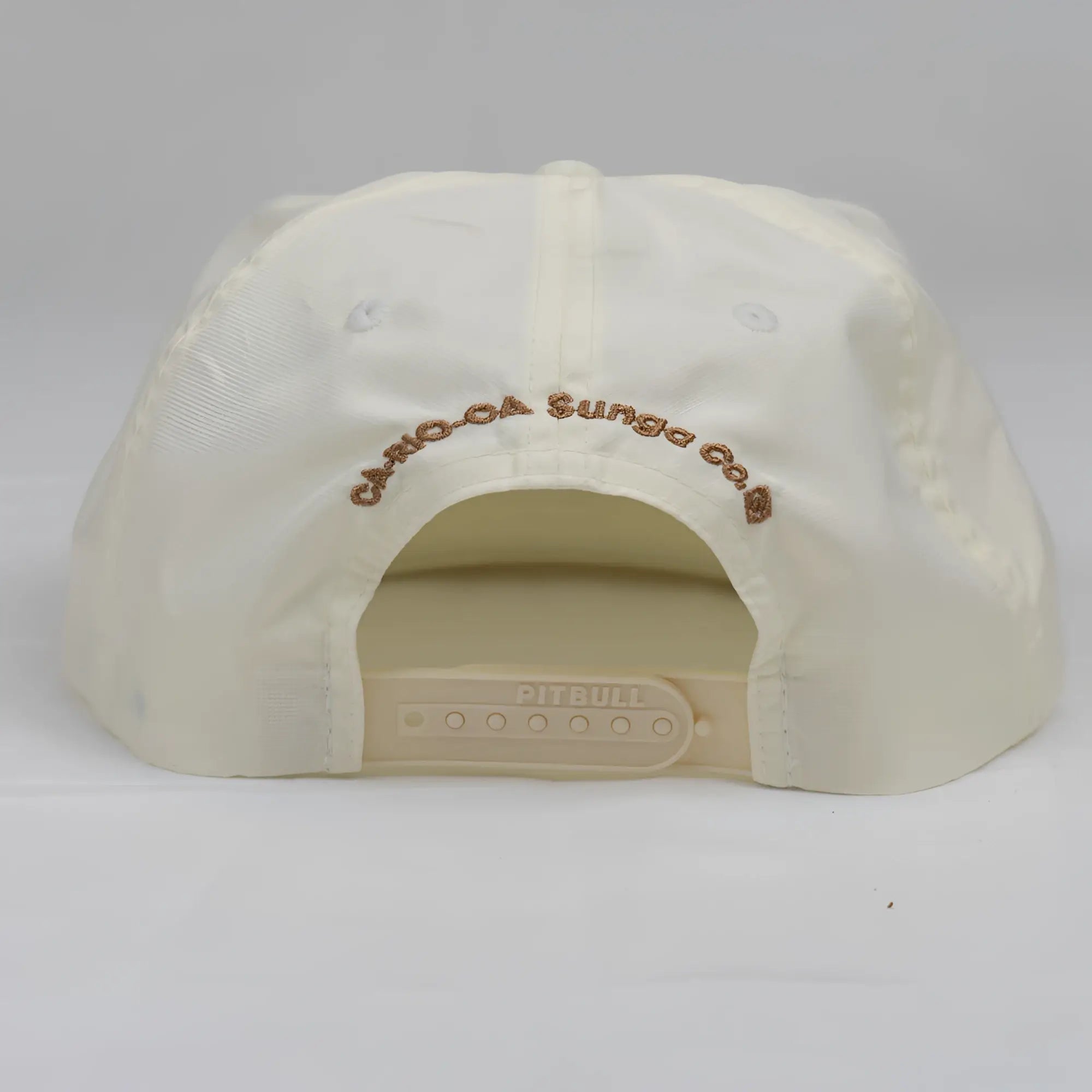 Cream-colored unstructured bay leaf snapback rope hat with brown embroidered crest logo and plastic adjustable strap