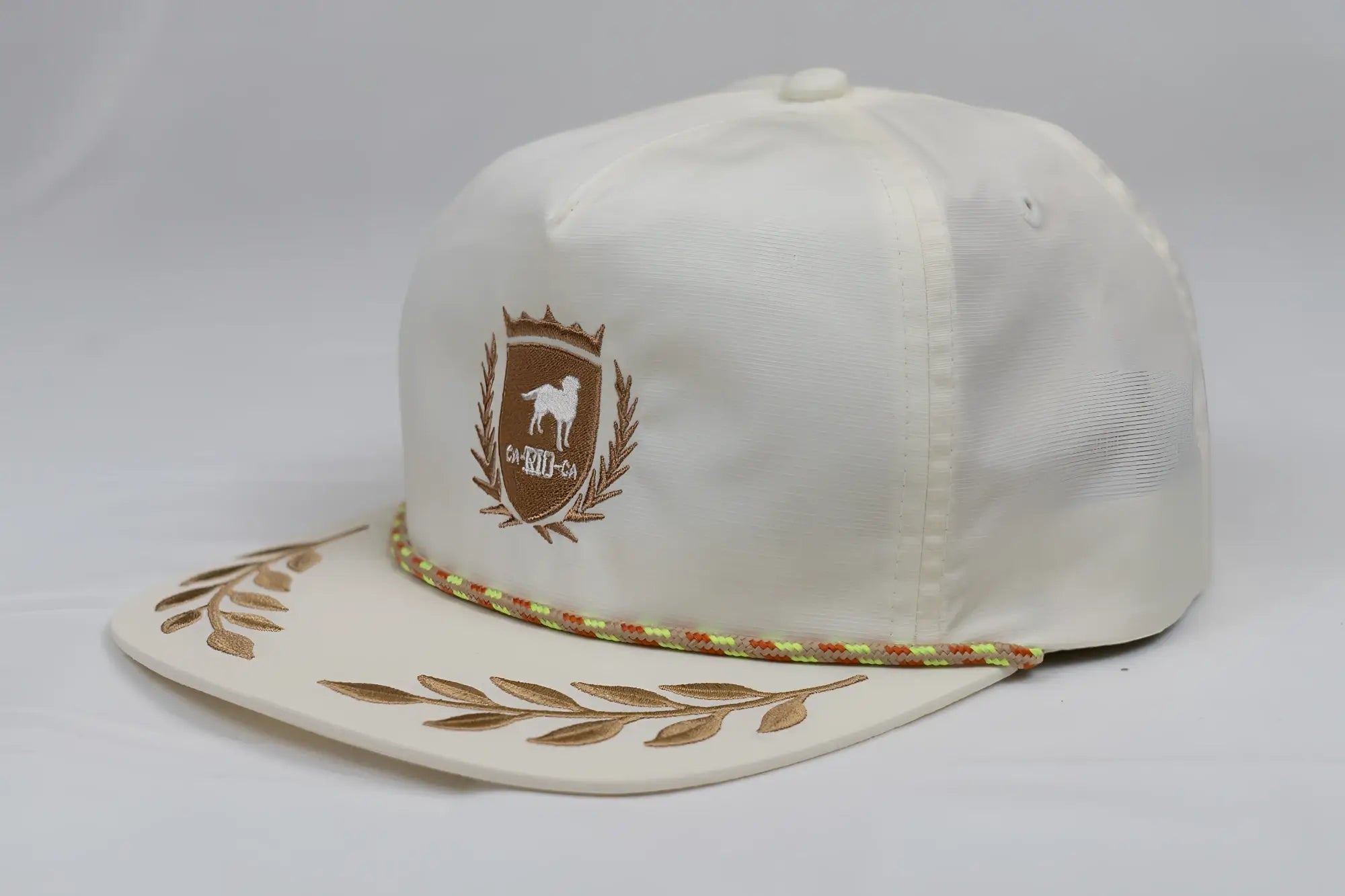 Cream-colored unstructured bay leaf snapback rope hat with brown embroidered dog crest and gold leaf brim accents