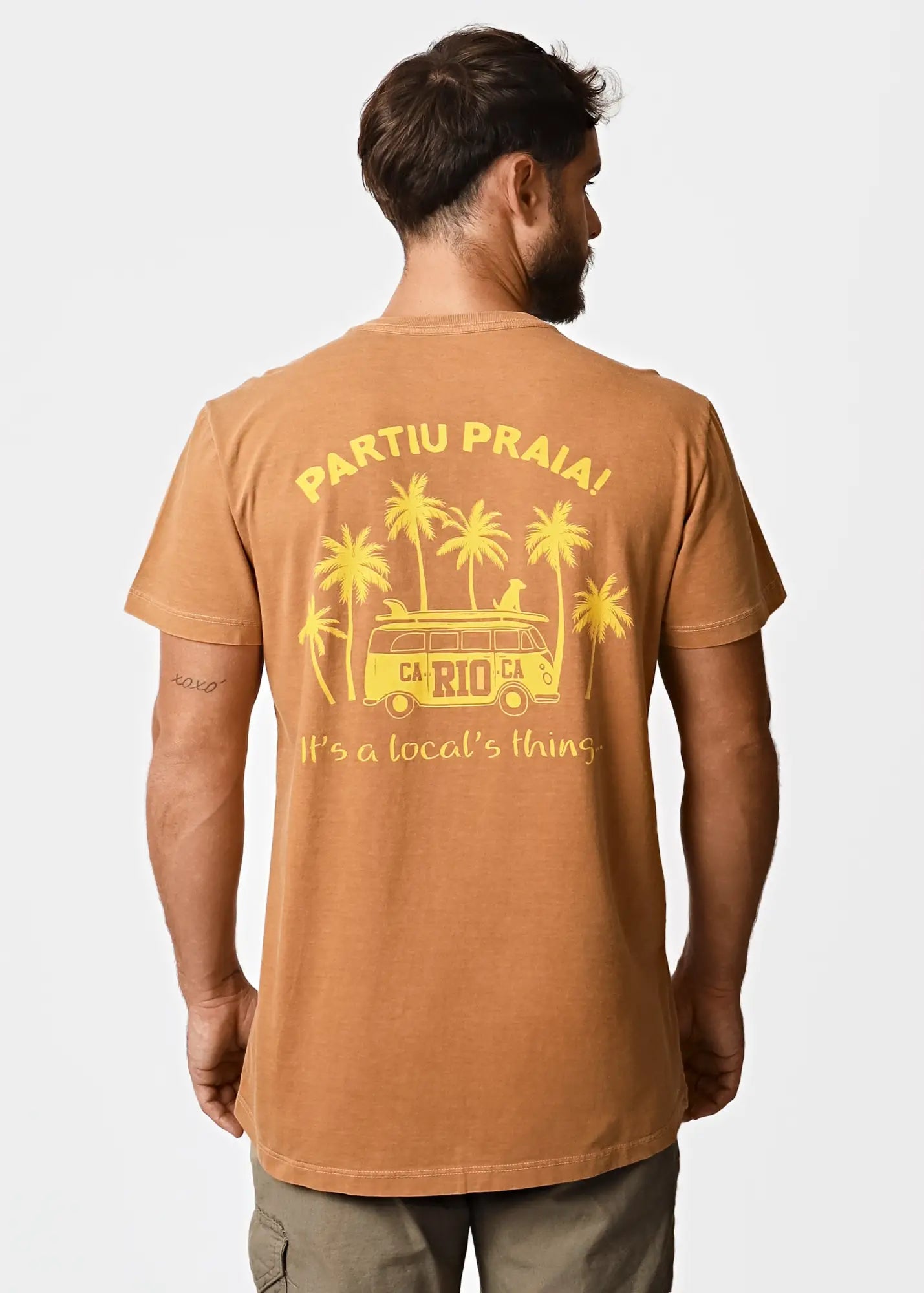 A mustard-yellow cotton men’s t-shirt featuring a vibrant yellow palm trees and vintage van graphic with carioca text
