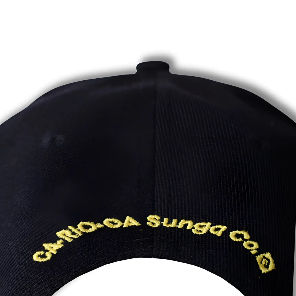 Black baseball hat with gold embroidered carioca sunga co logo along the curved brim in CA-RIO-CA style