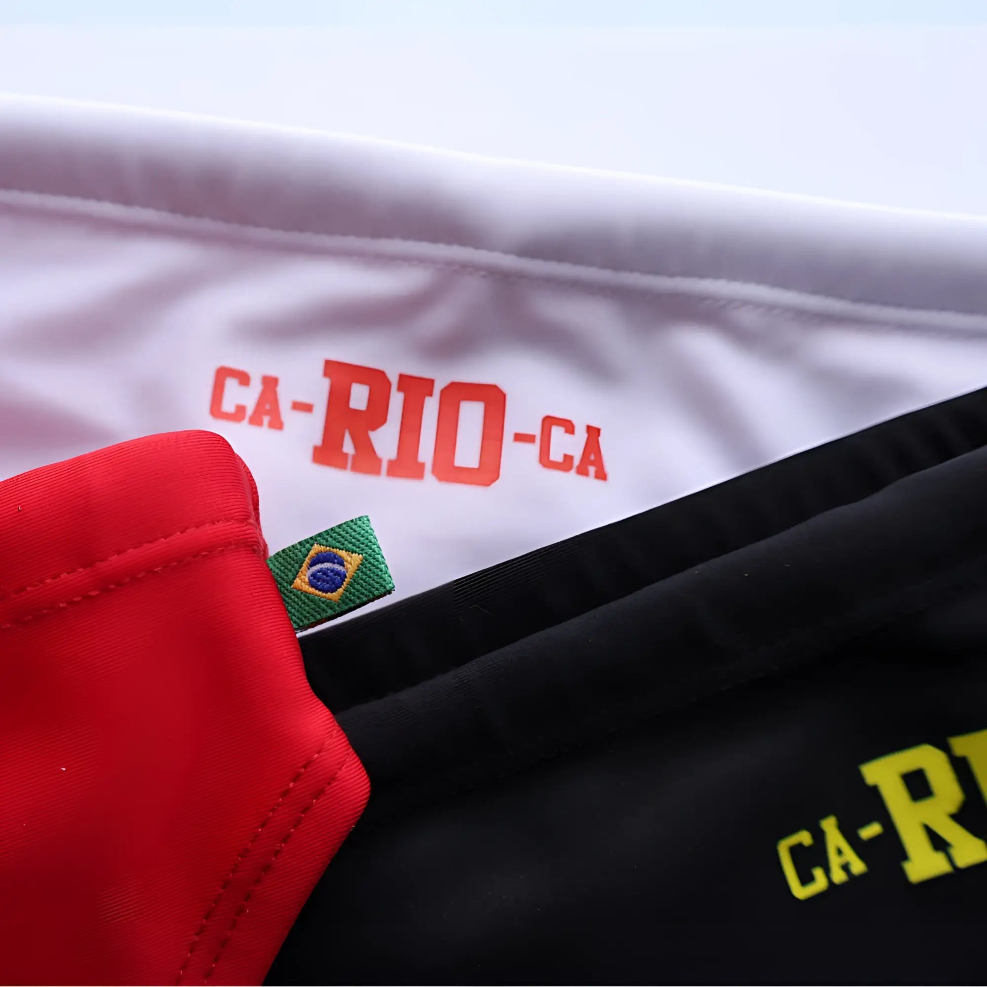 White athletic jersey with red ca-rio-ca lettering and green brazilian flag patch on sleeve for men’s beachwear