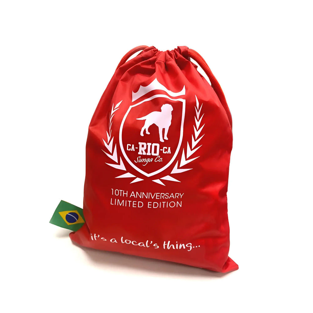 Red drawstring travel bag with white dog silhouette logo shield design and ca-rio-ca sunga co branding limited edition