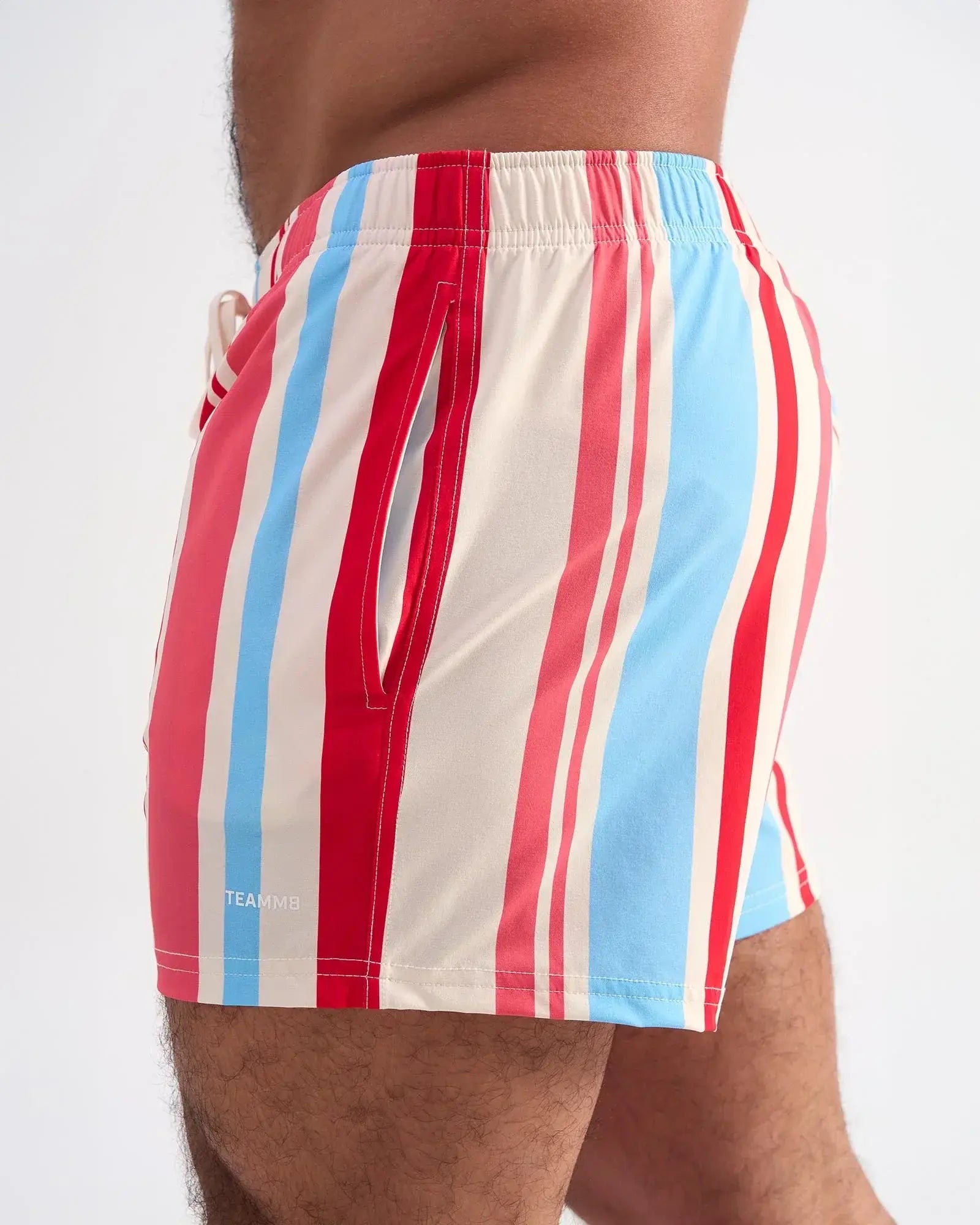 Cabana swim short featuring red light blue and cream vertical stripes with a side pocket and elastic waistband