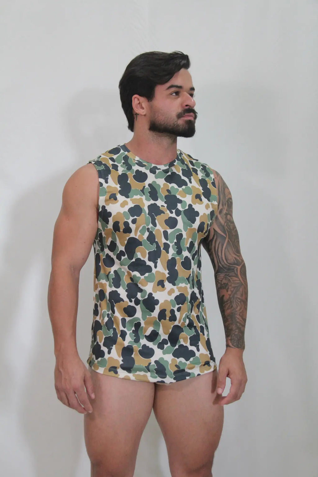A men’s sleeveless tank top with a green brown and black camouflage pattern on a white base called camouflage open arm tank
