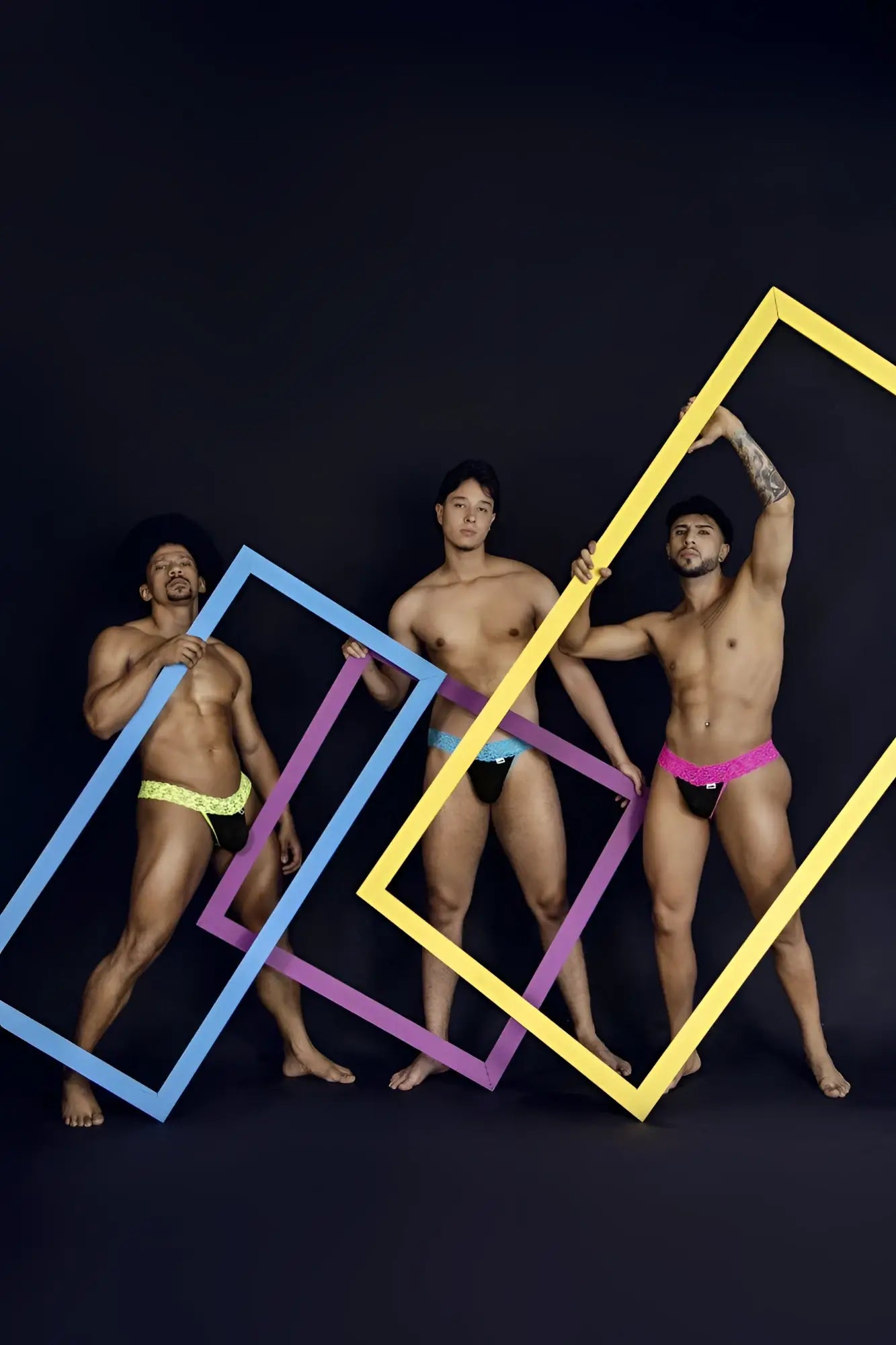 Three men pose with colorful oversized frames highlighting candyman 99370 lace thongs in blue color