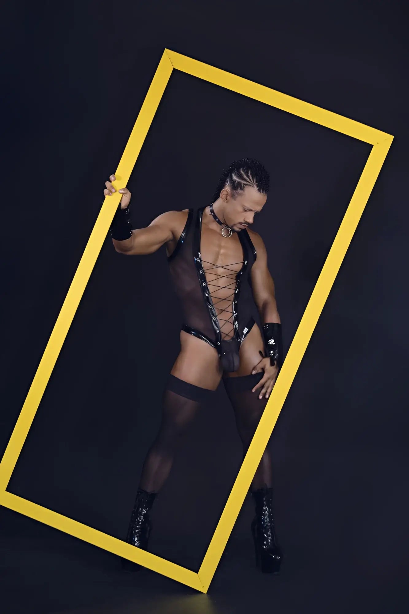 A bold yellow rectangular frame highlighting the black CandyMan 99774 Gladiator bodysuit in flexible material