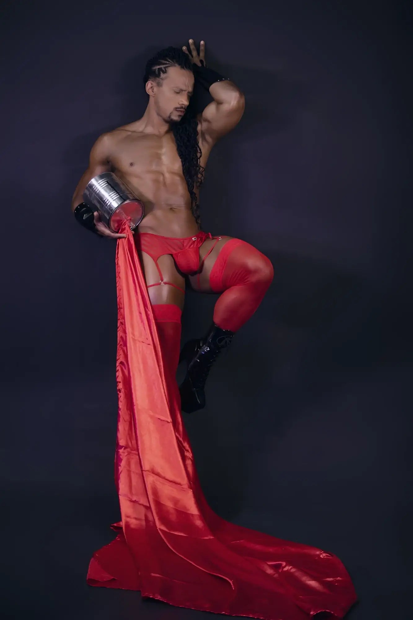 Shiny red satin fabric flowing from a man’s leg wearing candyman 99792 mesh garter thongs in red back view