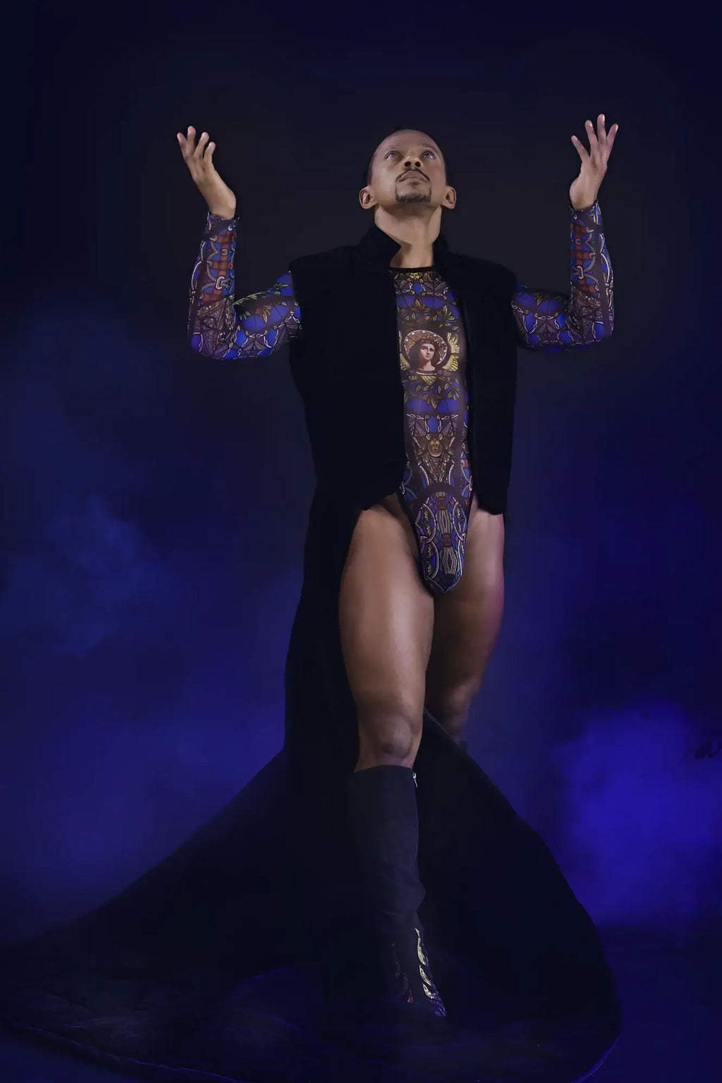 A man wearing a black vest over a colorful patterned stained glass bodysuit with blue and gold designs candyMan 99814