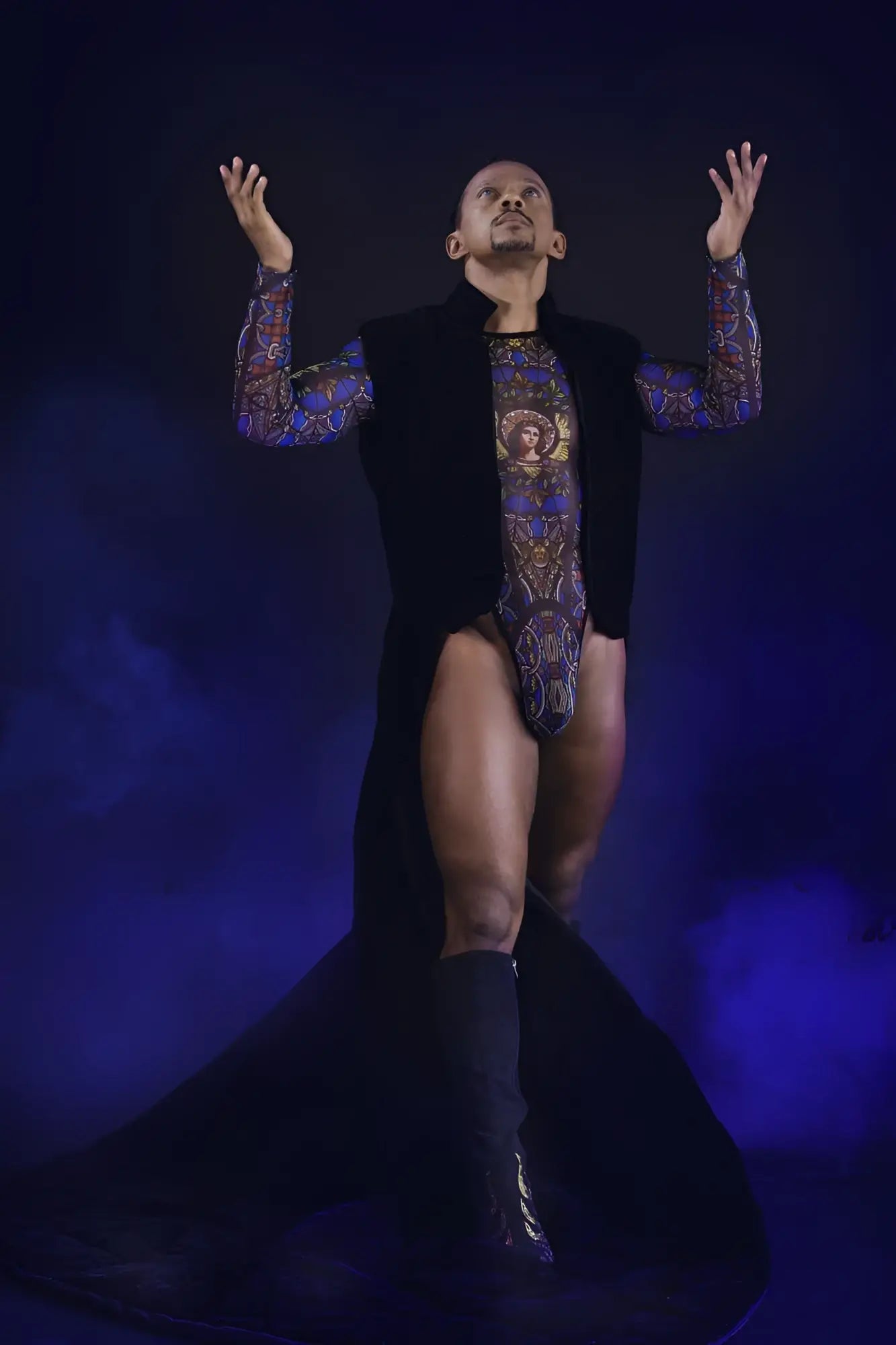 A man wearing a black vest over a colorful patterned stained glass bodysuit with blue and gold designs candyMan 99814