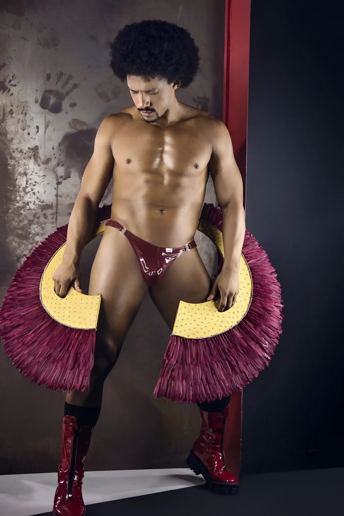 A shiny maroon latex CandyMan 99819 dom thong with bold fringed magenta and yellow circular side accessories