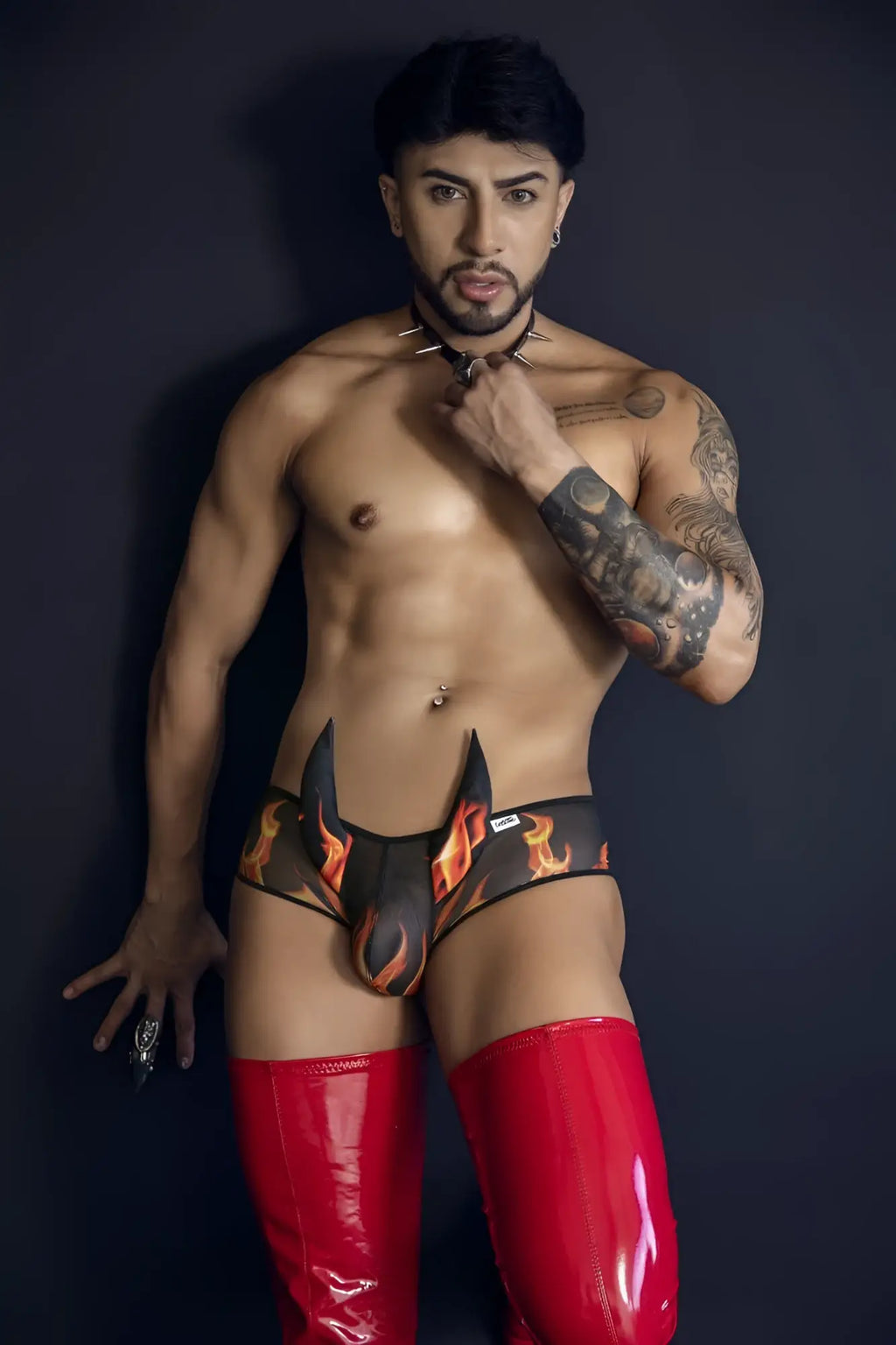 Black and orange flame patterned CandyMan 99917 Wicked Trunks briefs paired with glossy red latex thigh-high boot