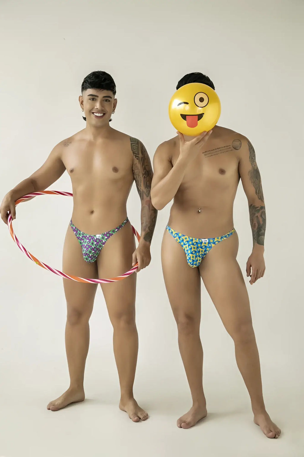 The man on the left wears candyman 99924 thongs color printed purple floral patterned briefs in vibrant shades of purple