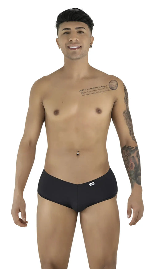 A smiling man poses against a white background, wearing black CandyMan trunks with a V-cut waistband.