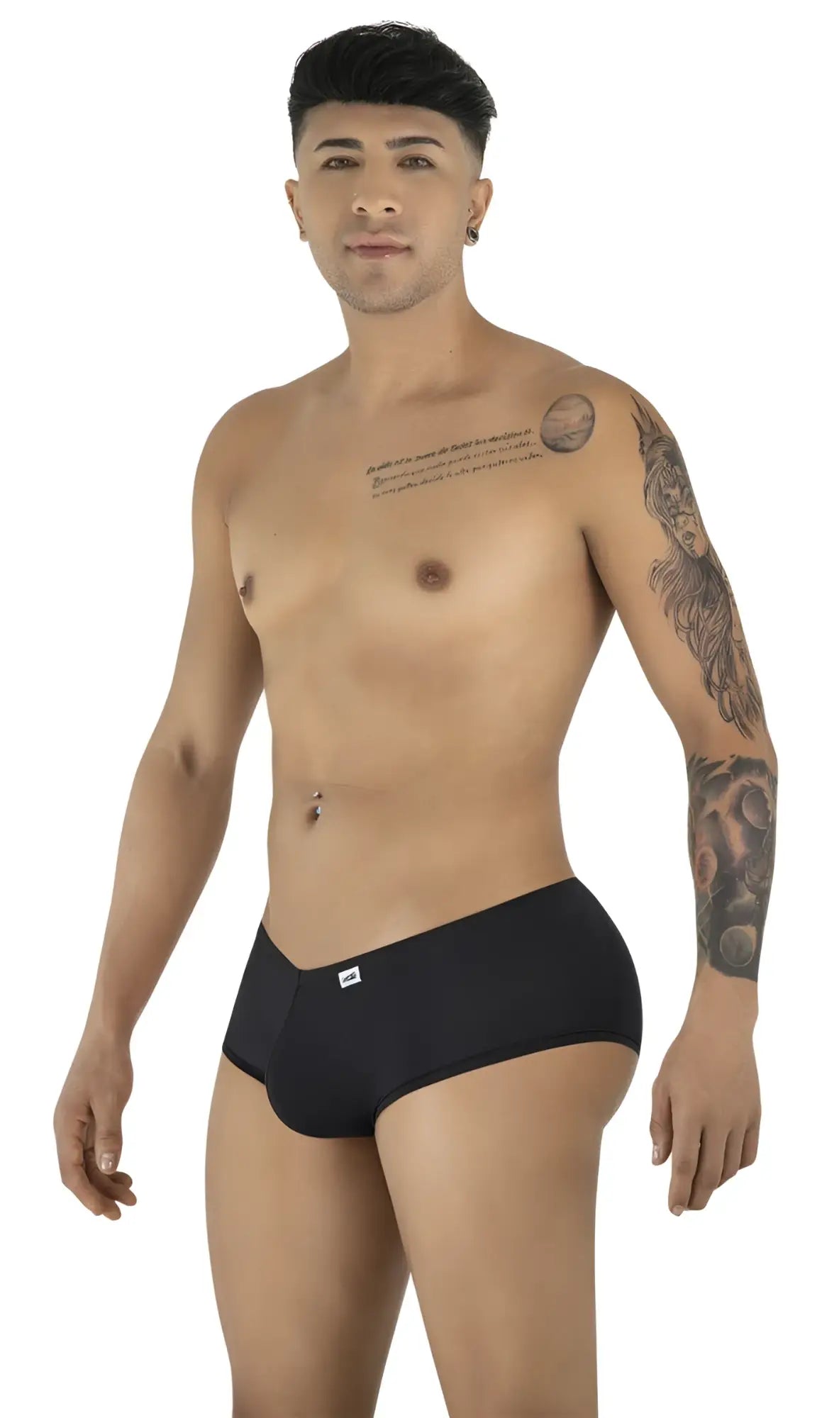 A man with chest and arm tattoos posing in black CandyMan 99943 trunks against a white background.