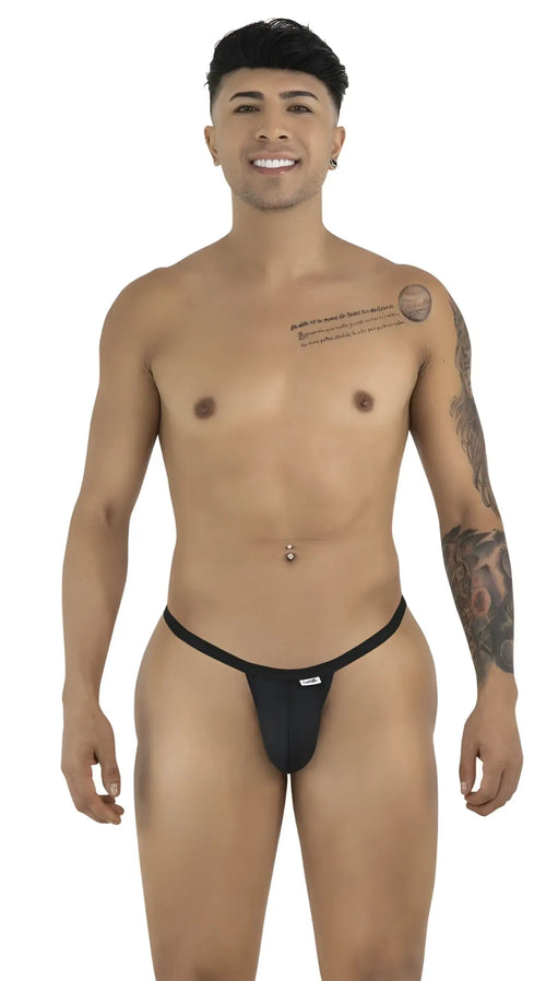 A smiling man with tattoos and a navel piercing models a minimalist black CandyMan thong against a white background.