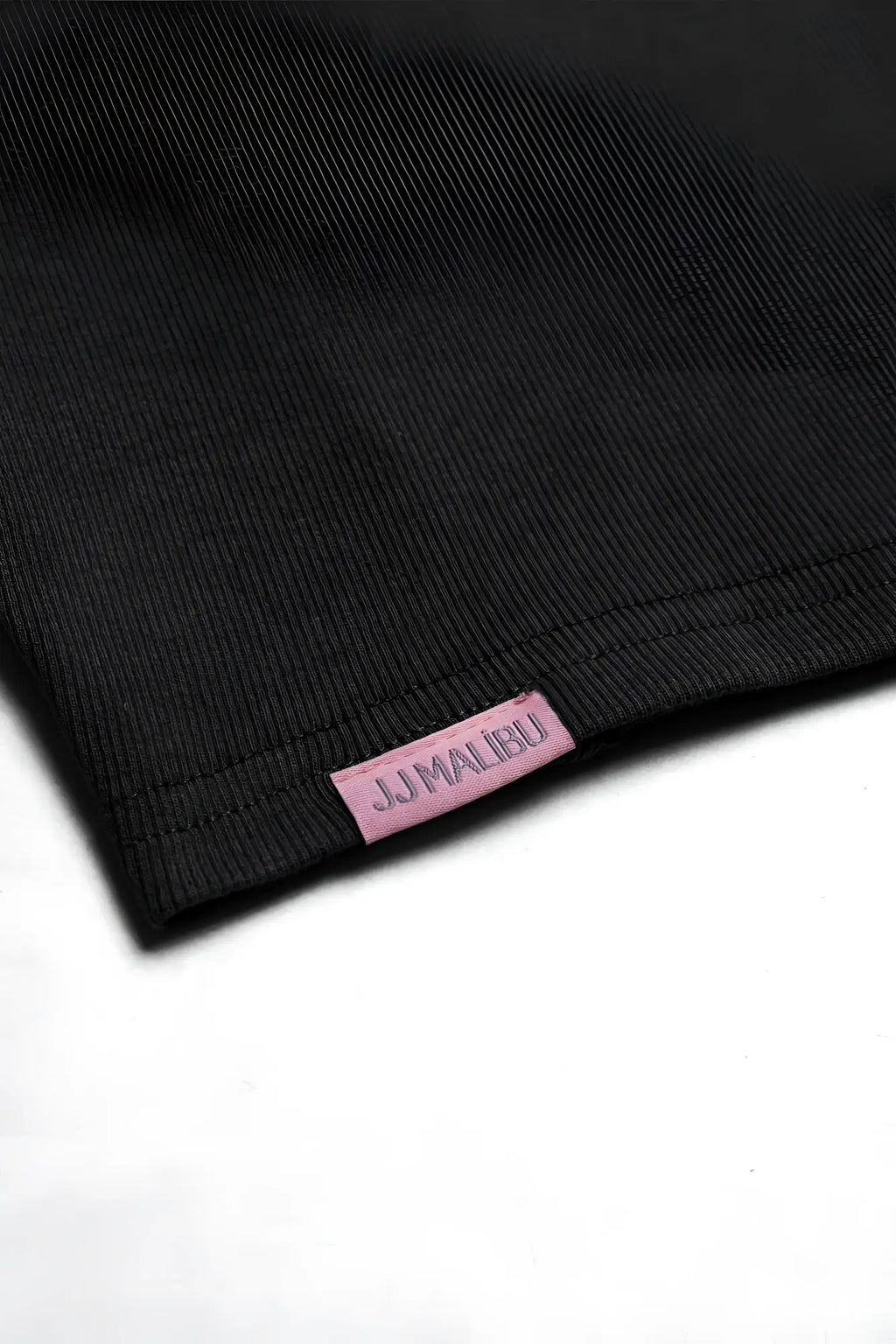 Black ribbed cotton cap sleeve crop top with pink jjmalibu brand tag visible in close-up view