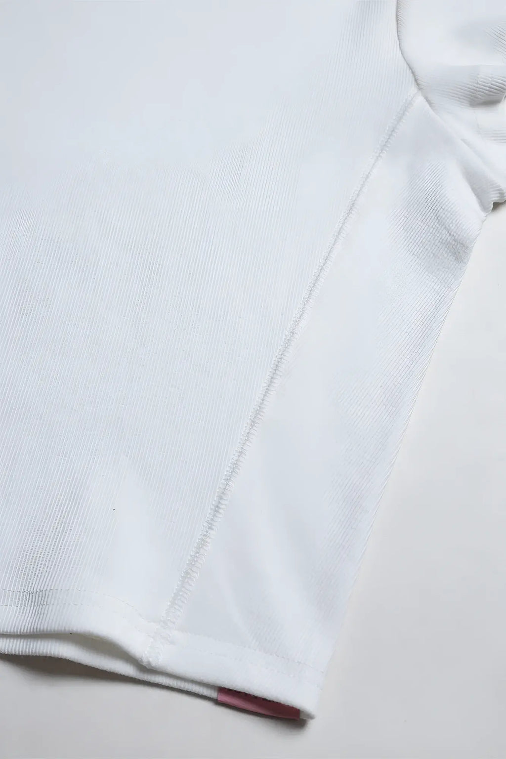 White rib knit cap sleeve crop top with subtle seam and small red tag at the hem in ivory color