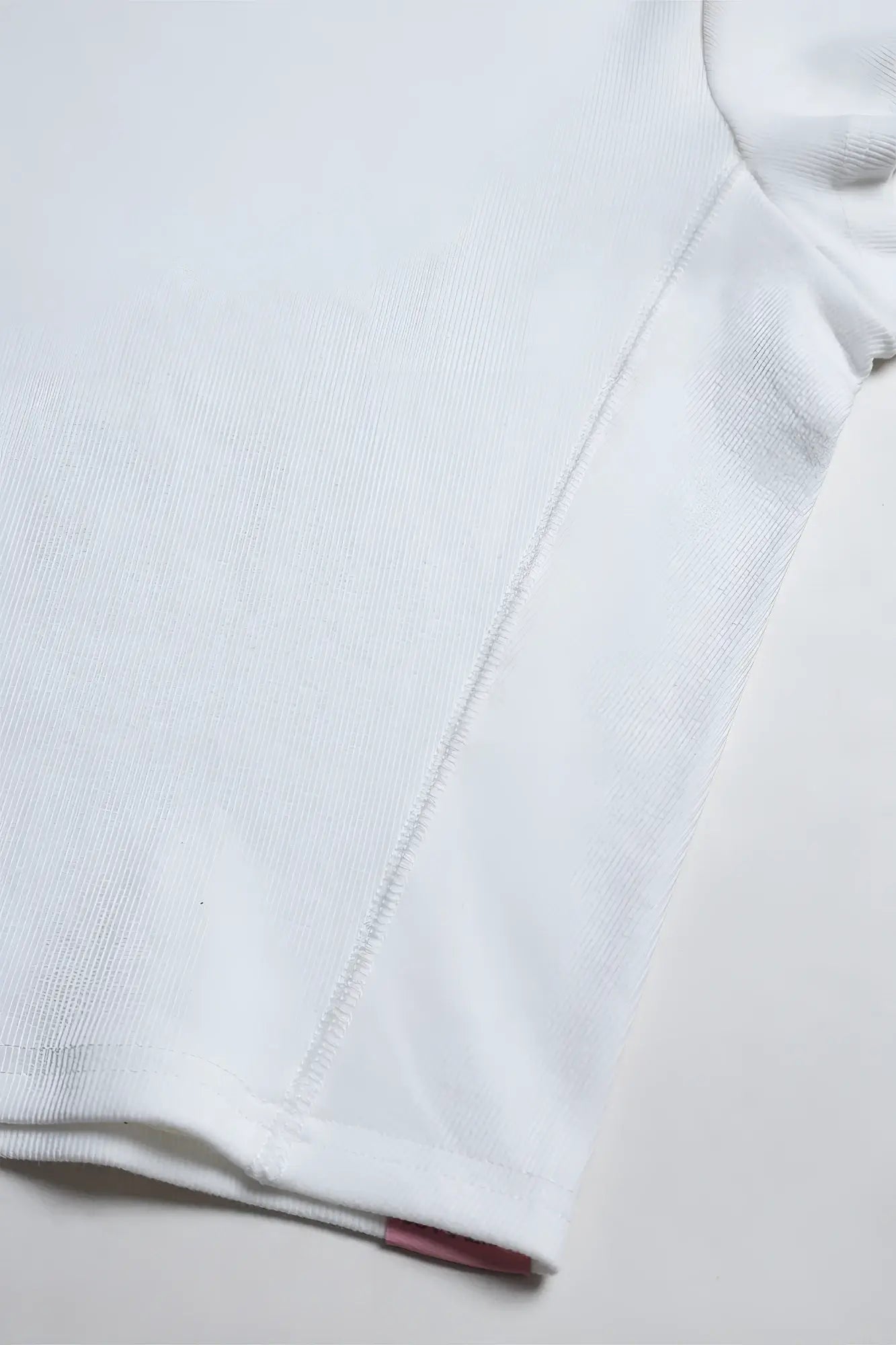 White rib knit cap sleeve crop top with subtle seam and small red tag at the hem in ivory color