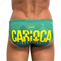 Teal swim trunks with bold yellow carioca festival lettering and christ the redeemer silhouette for rio beachwear