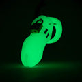 CB-X CB-6000 glow-in-the-dark green chastity cage with a metal padlock, set against a dark background.