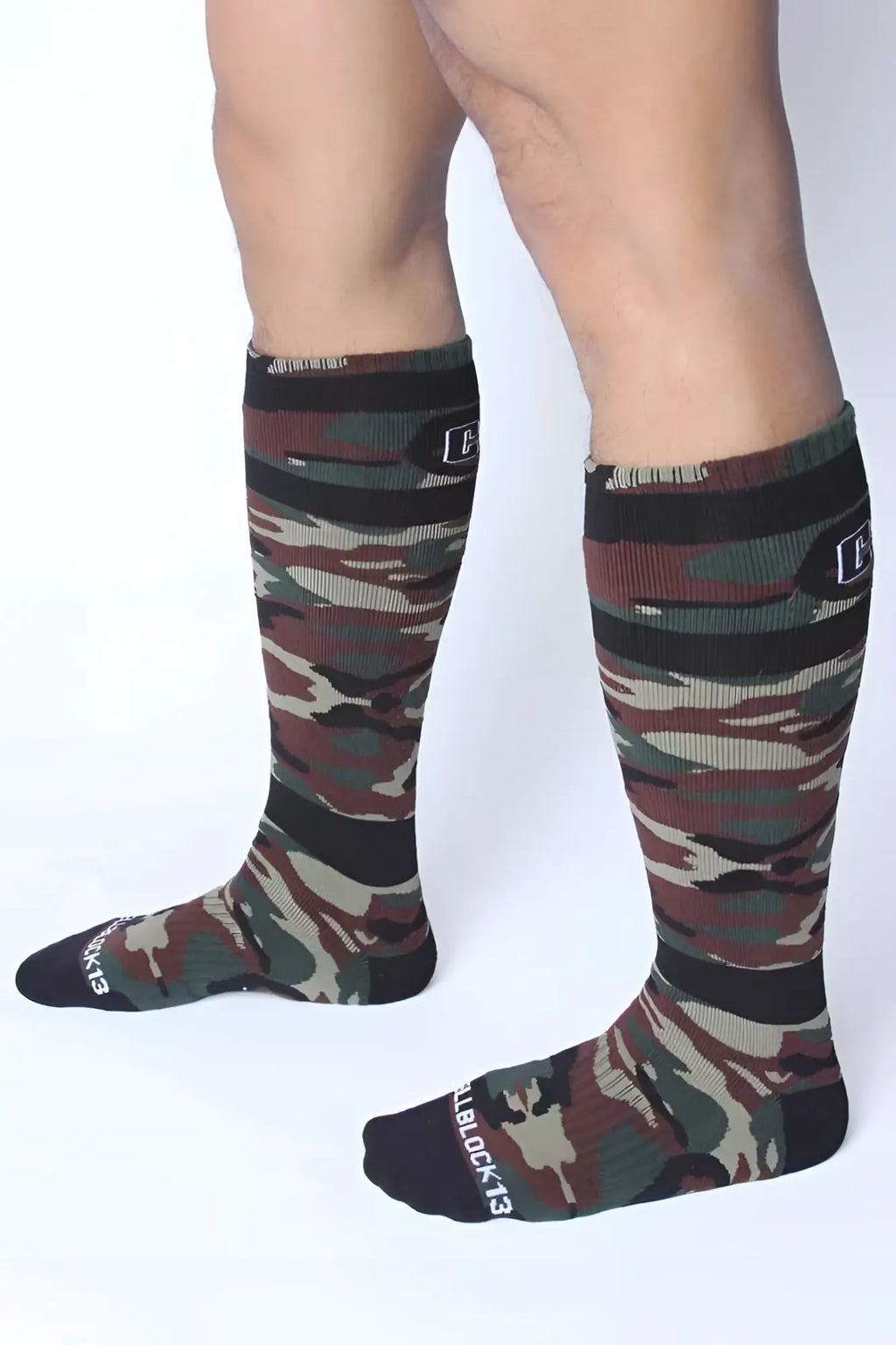 Camouflage-patterned knee-high foxhole socks in green with black ribbed cuffs and toe caps by cellblock 13 size one size