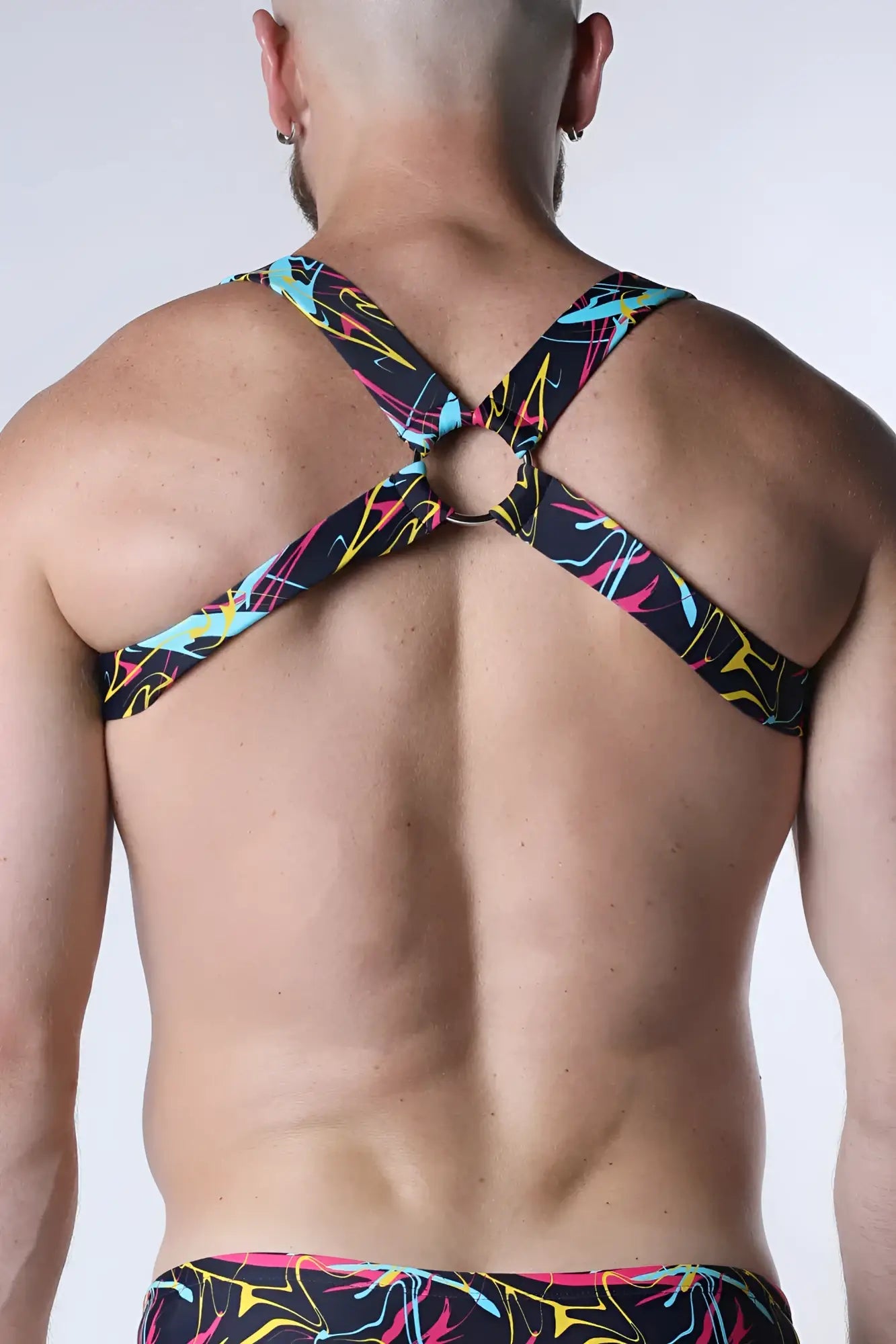 Black neon-colored abstract patterned strappy backless pulse elastic harness top with central circular metal ring back view