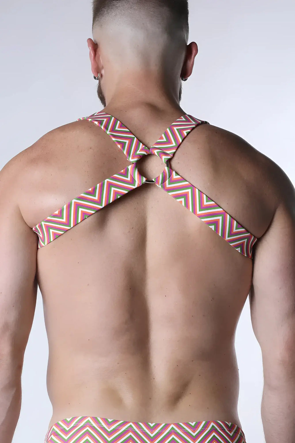 A man wearing the back side of a pulse elastic harness with red white and green zigzag pattern and crossed shoulder straps