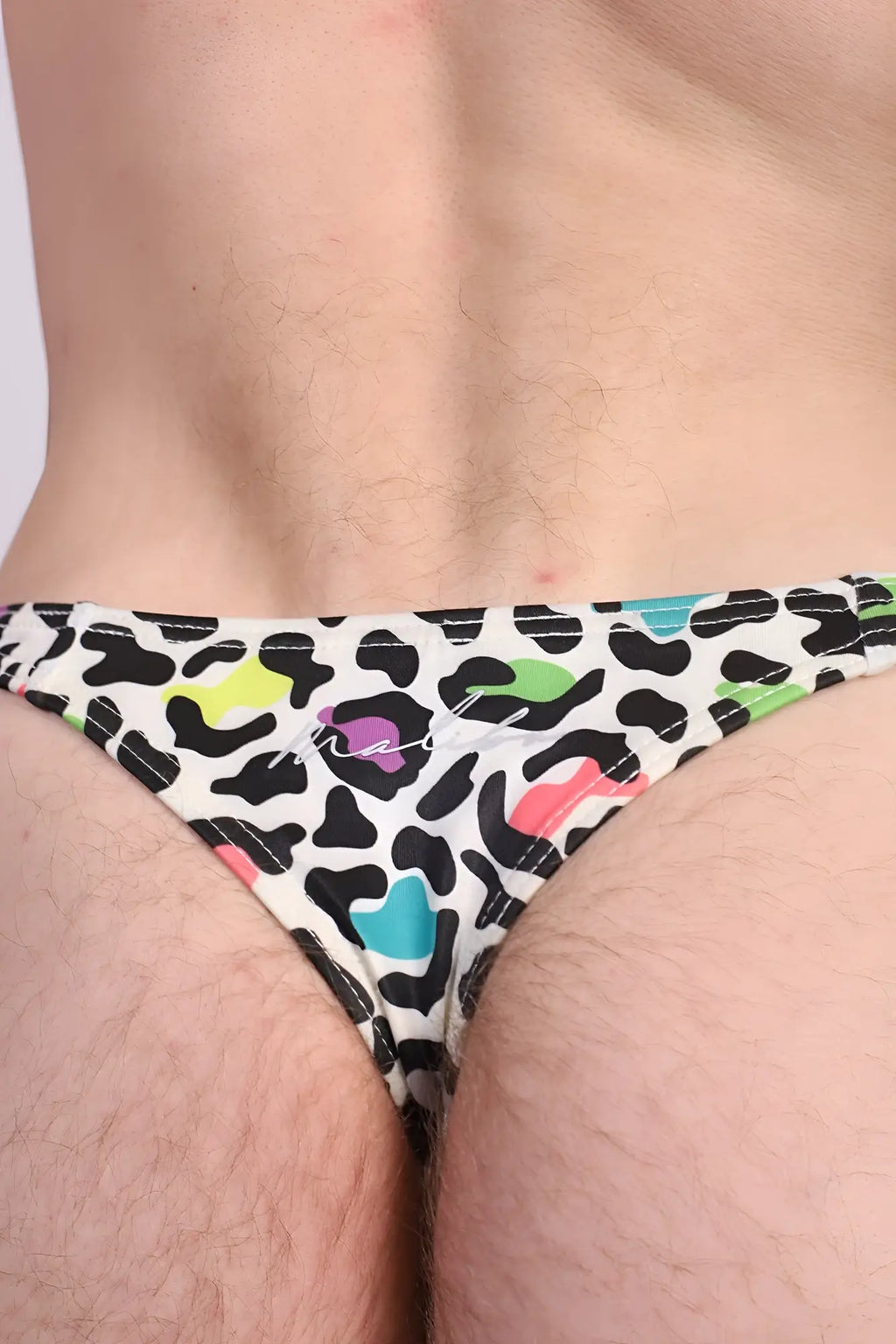Cheeky classic g-string thong in vibrant rainbow leopard print with black spots and neon splashes on white base back view