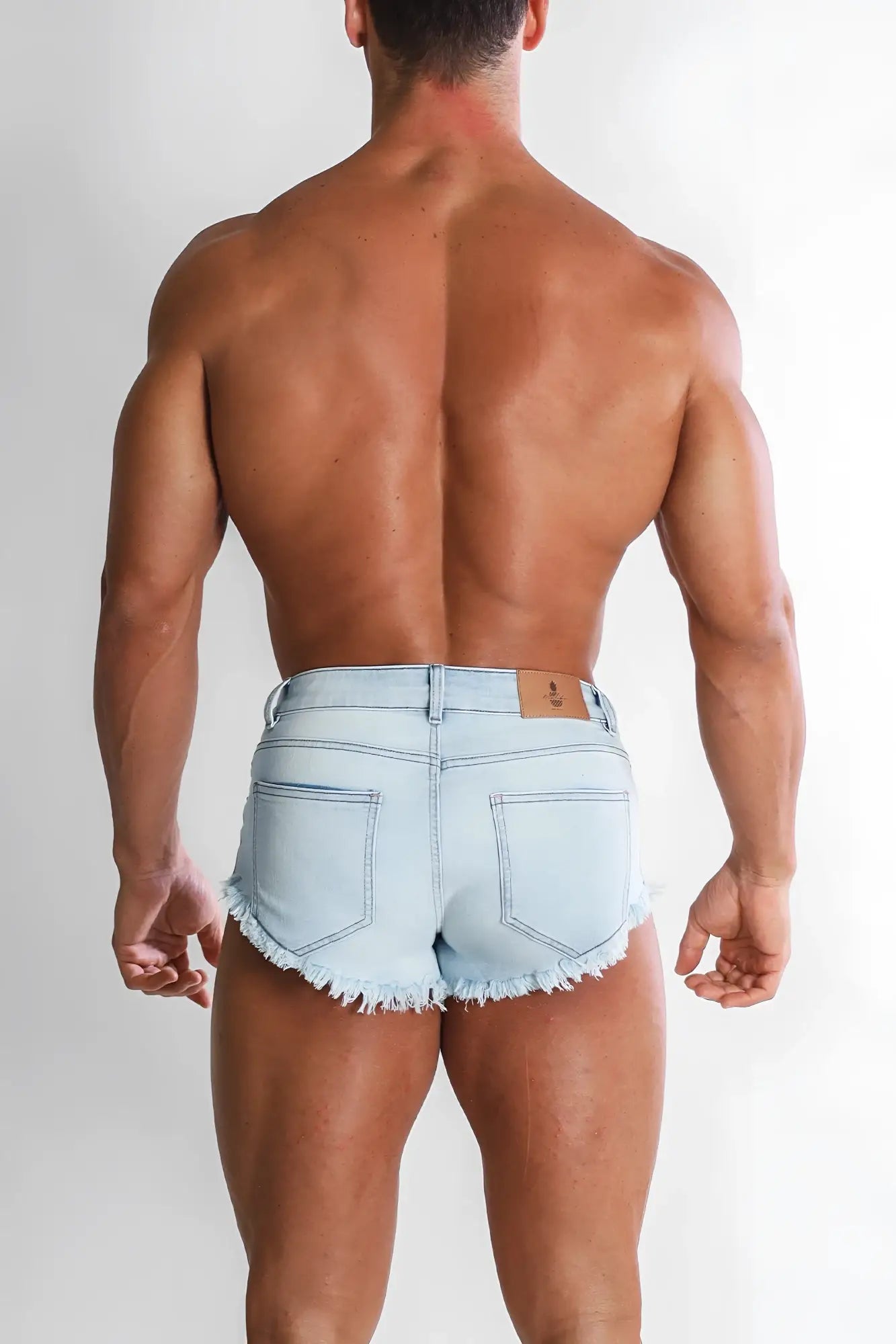 Light-wash denim shorts with frayed hem and back pockets shown from the back in sky blue cheeky summer brief style