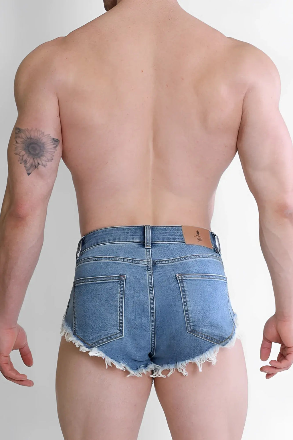 Blue denim cheeky summer 2.5 inch brief shorts with frayed hem and back pockets shown from the back side