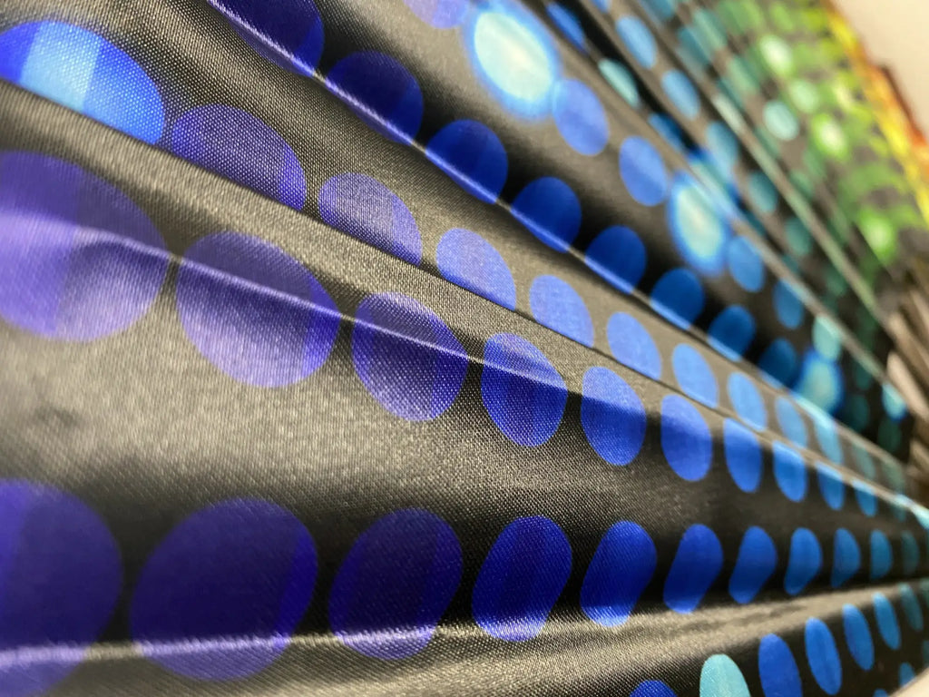 Black fans fabric with overlapping blue circles pattern in varying shades featuring smooth texture and subtle sheen