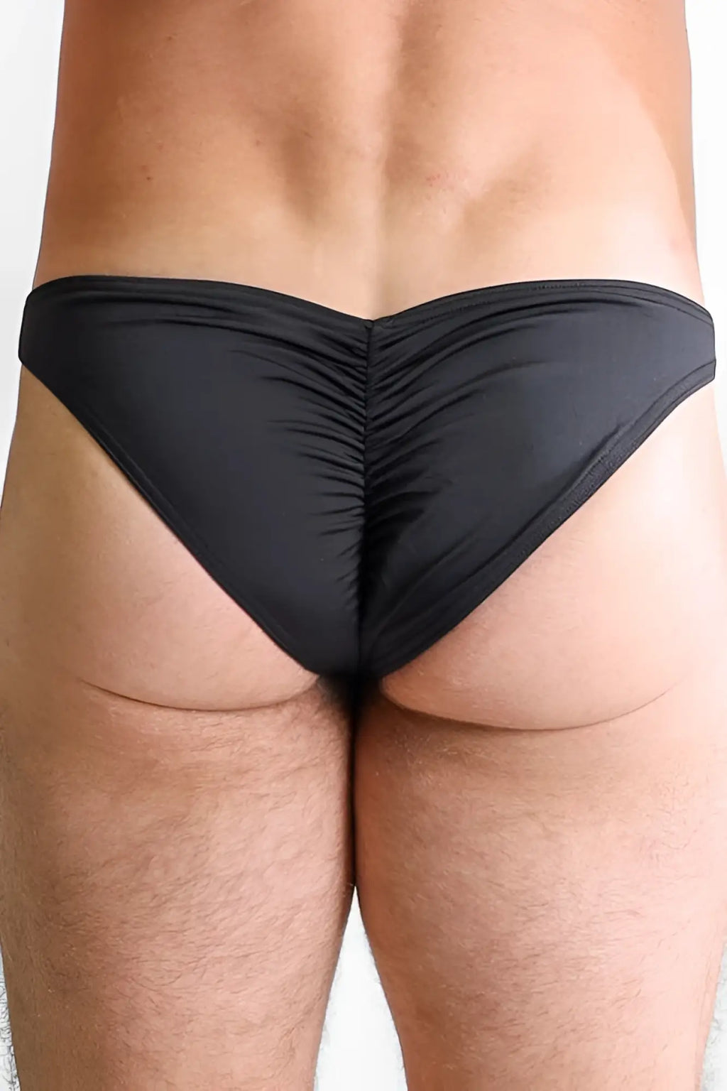 Black ruched swim trunks showing the back side of classic scrunch-butt swim briefs for men