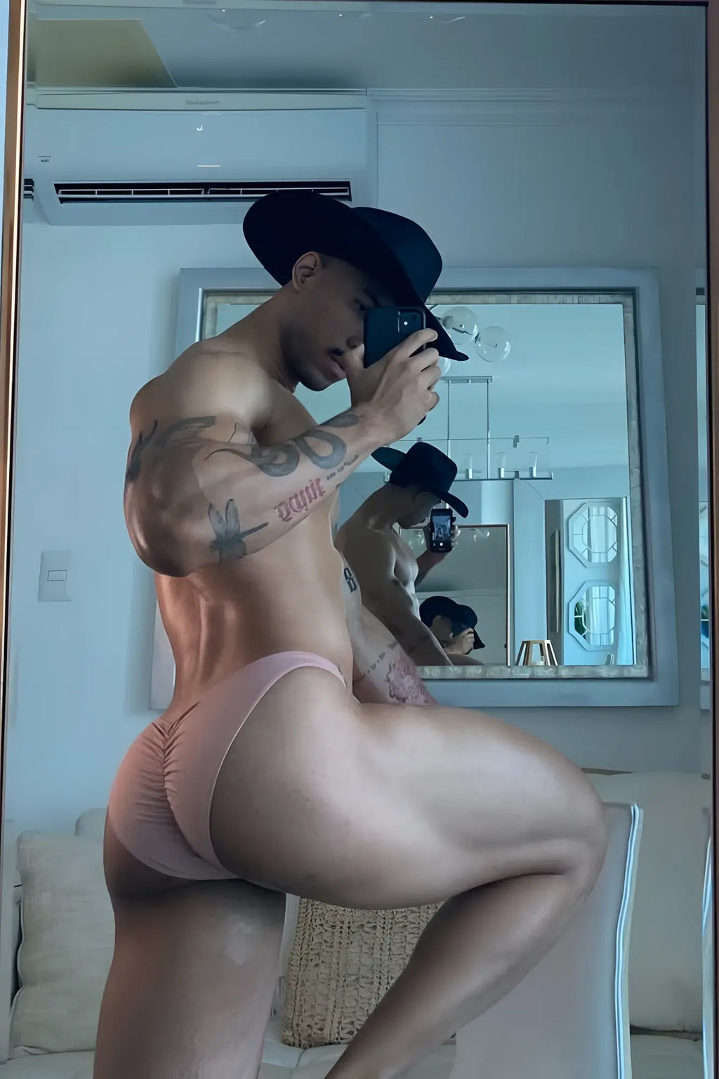A man wearing a black cowboy hat showing the back side of classic scrunch-butt swim briefs in nude pink