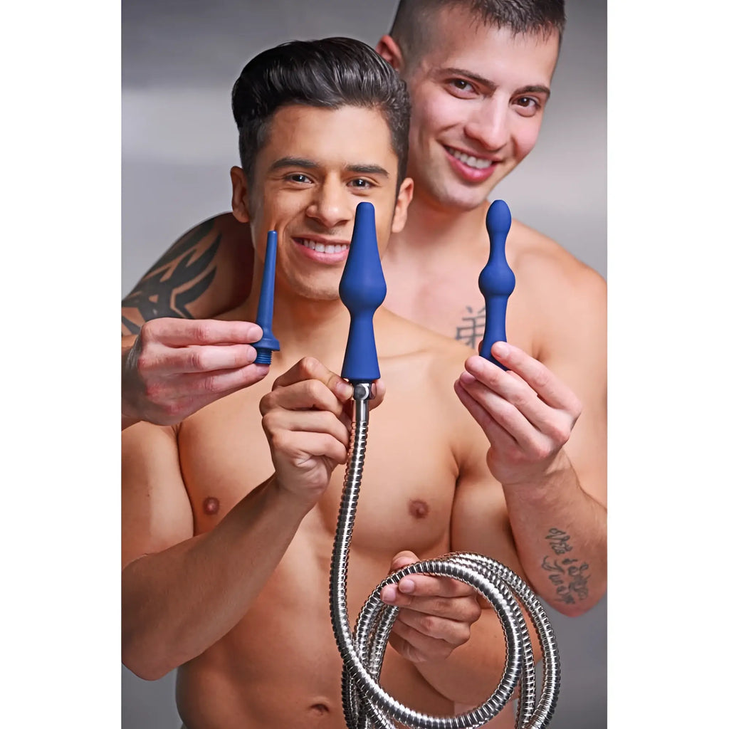 Two shirtless men smiling while holding a CleanStream 3pc blue silicone enema attachment set with a metal hose.