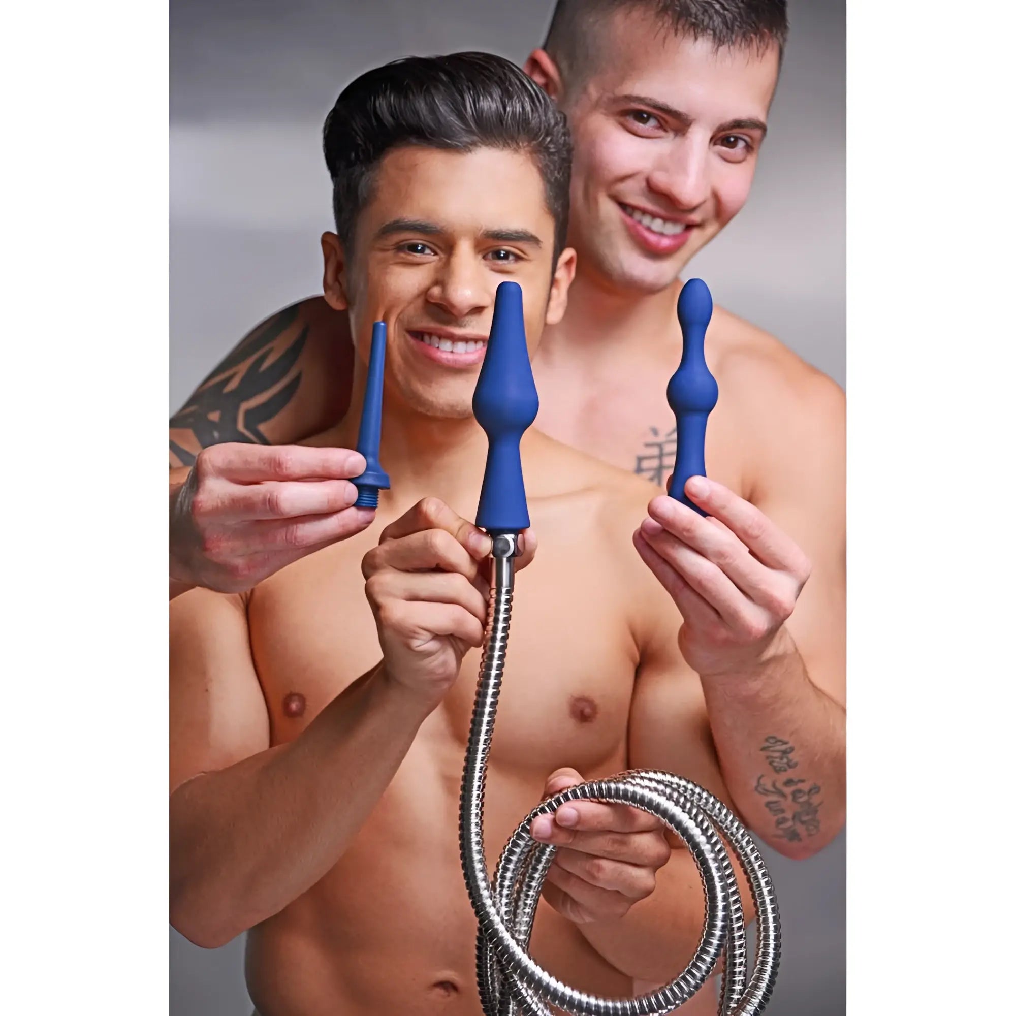 Two shirtless men smiling while holding a CleanStream 3pc blue silicone enema attachment set with a metal hose.