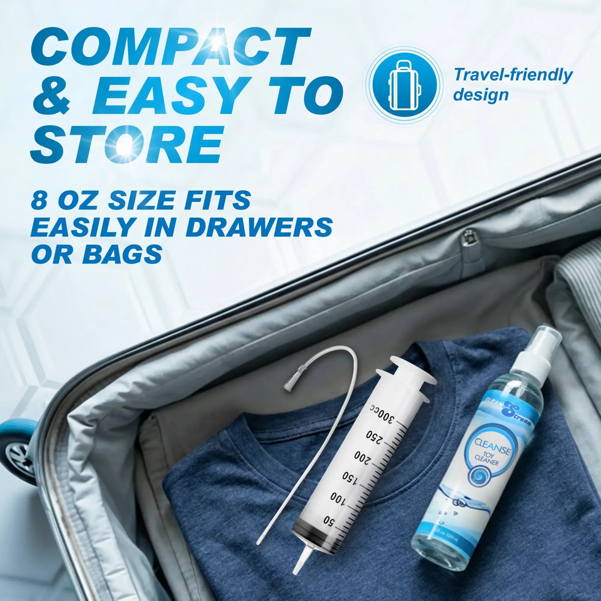 CleanStream 8oz toy cleaner spray bottle and syringe inside an open suitcase on top of folded blue clothing.