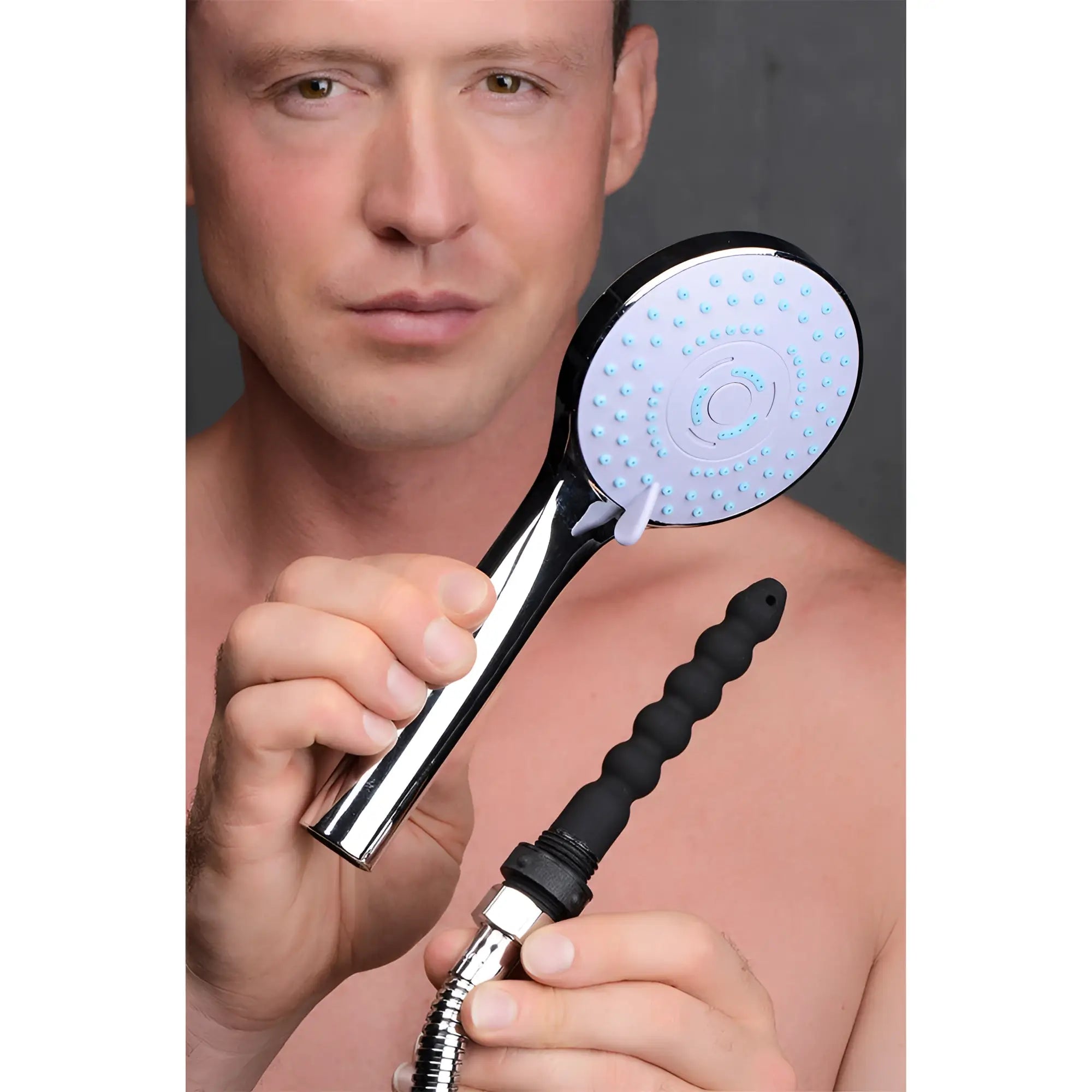 A man holding a chrome CleanStream shower enema set with a white spray head and a black ribbed silicone nozzle.
