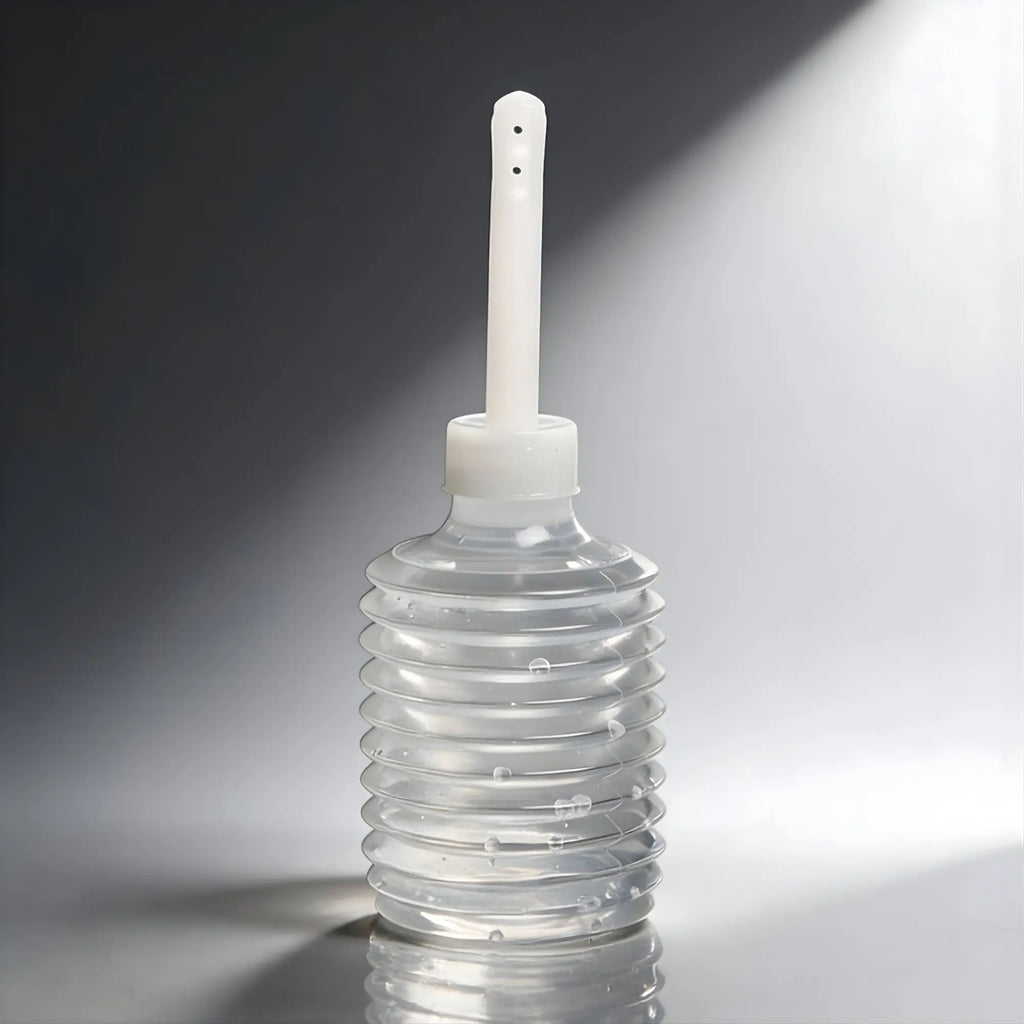 CleanStream disposable enema applicator: a clear, ribbed plastic squeeze bulb with a long, thin white nozzle.