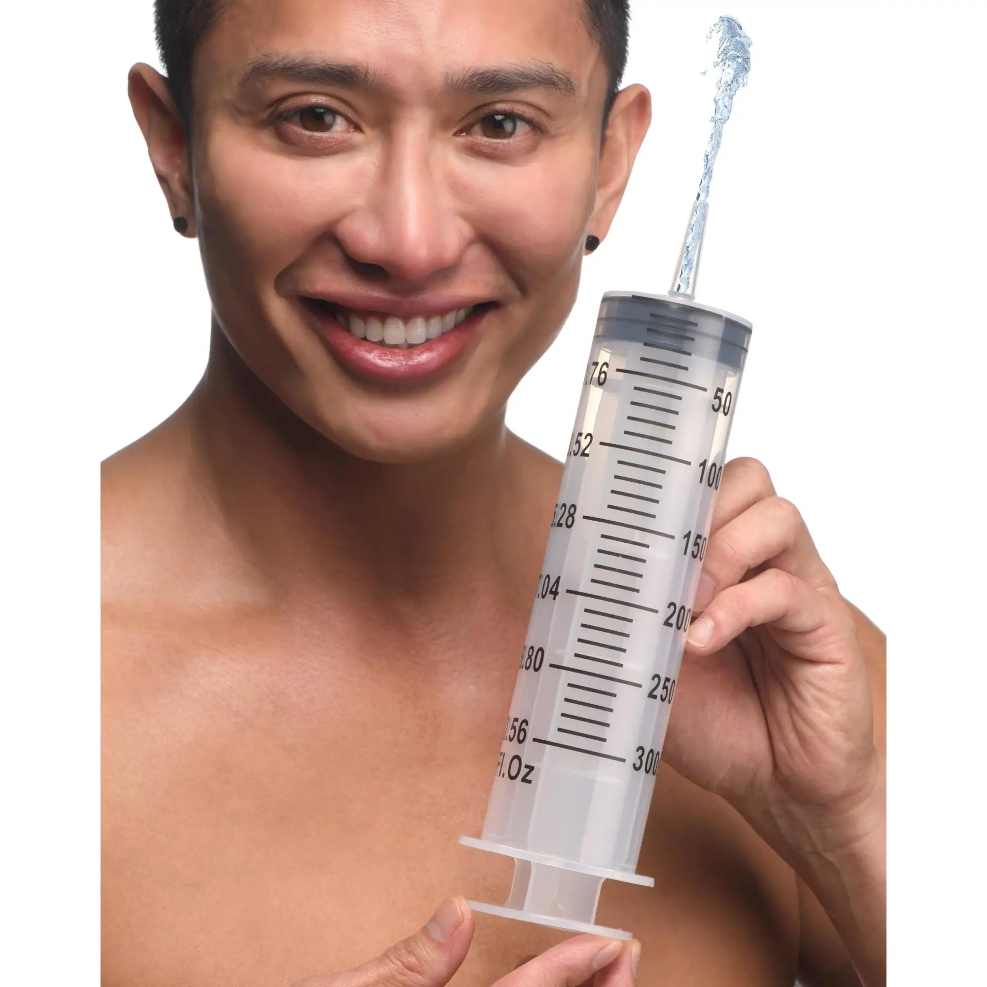 A smiling man holds a large, clear 300ml CleanStream enema syringe, with water spraying from the nozzle.