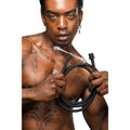A tattooed man holds a coiled, black CleanStream Premium Silicone Enema Hose with water spraying from the nozzle.