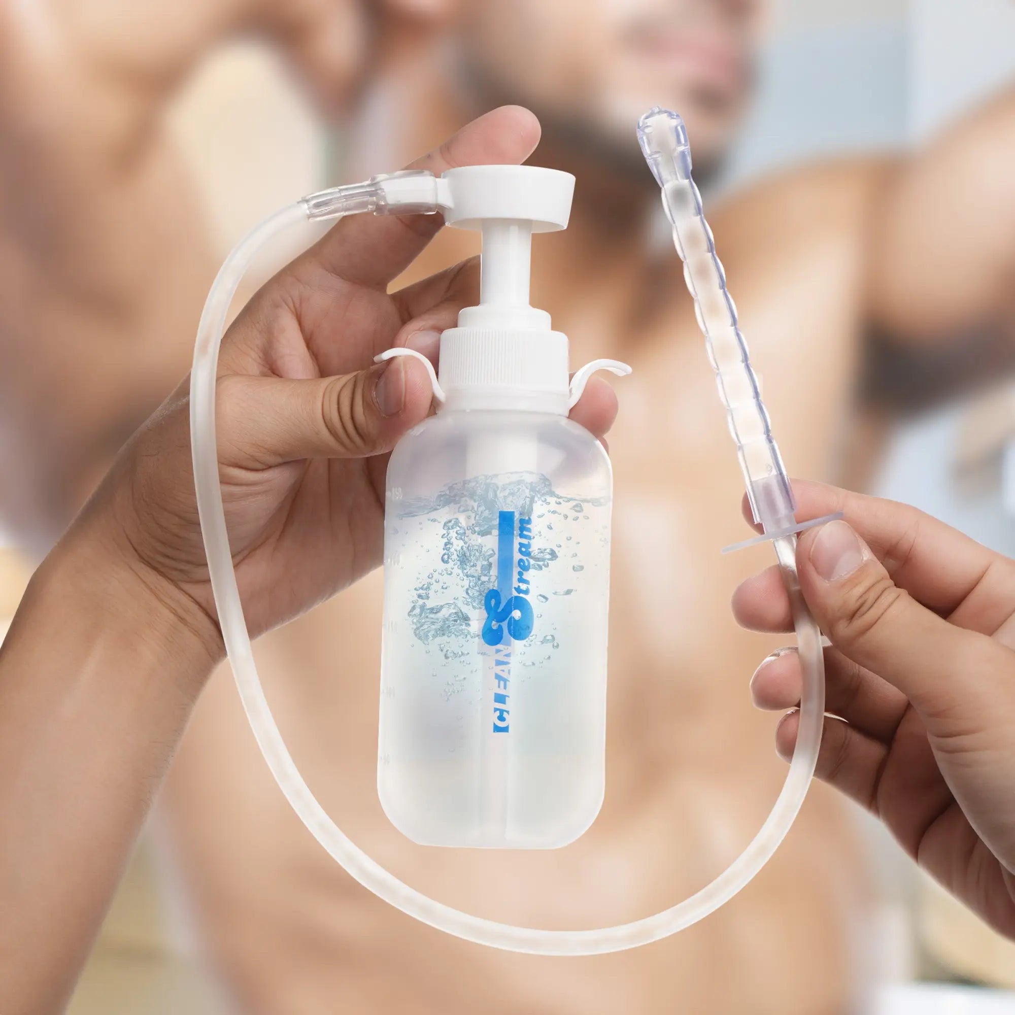 CleanStream pump-action enema bottle with white cap, clear tube, and ridged nozzle held by two hands.
