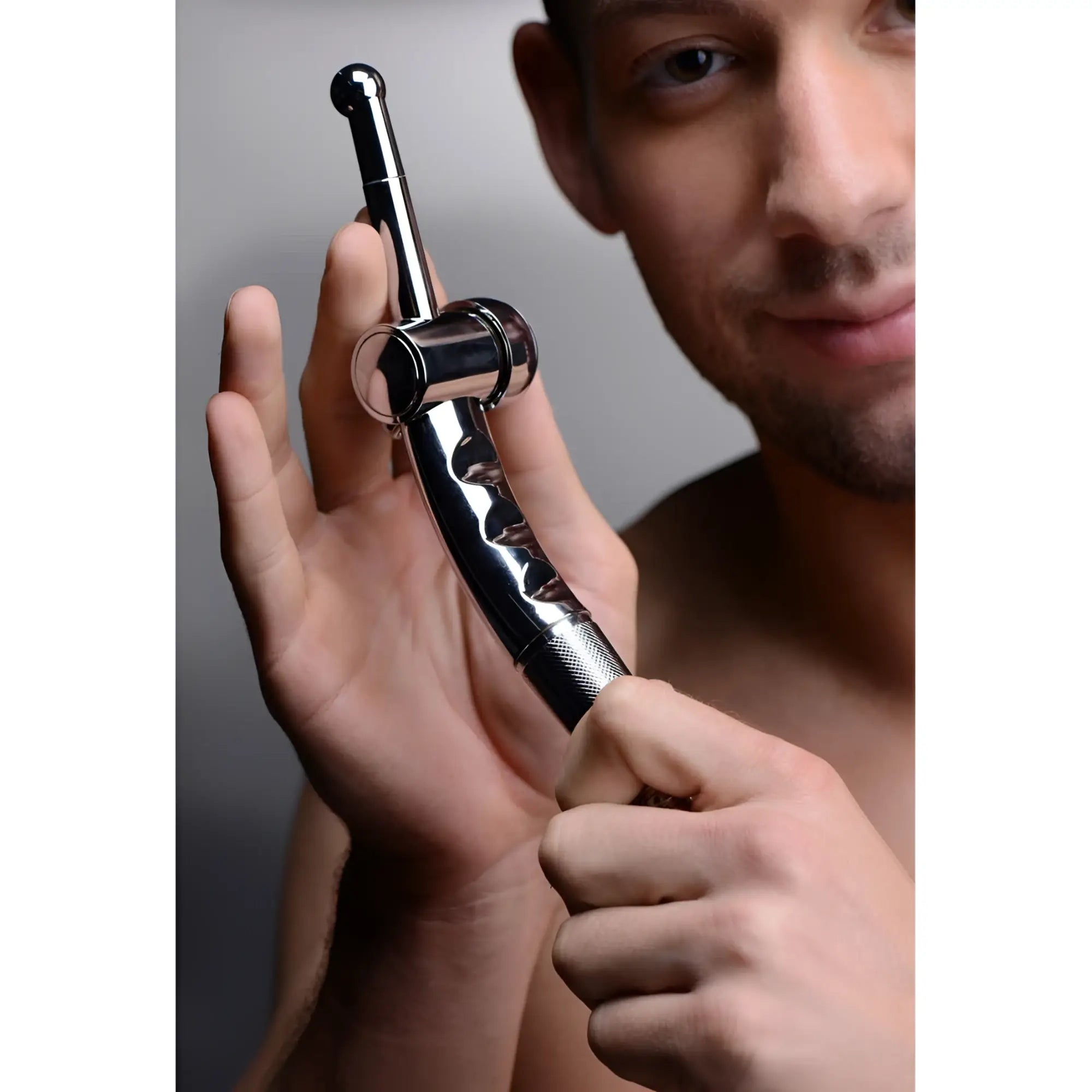 CleanStream chrome shower cleansing nozzle with flow regulator held by a man.