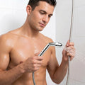 A man in a shower holds a chrome CleanStream Shower Enema Wand, which sprays water from its rounded tip.